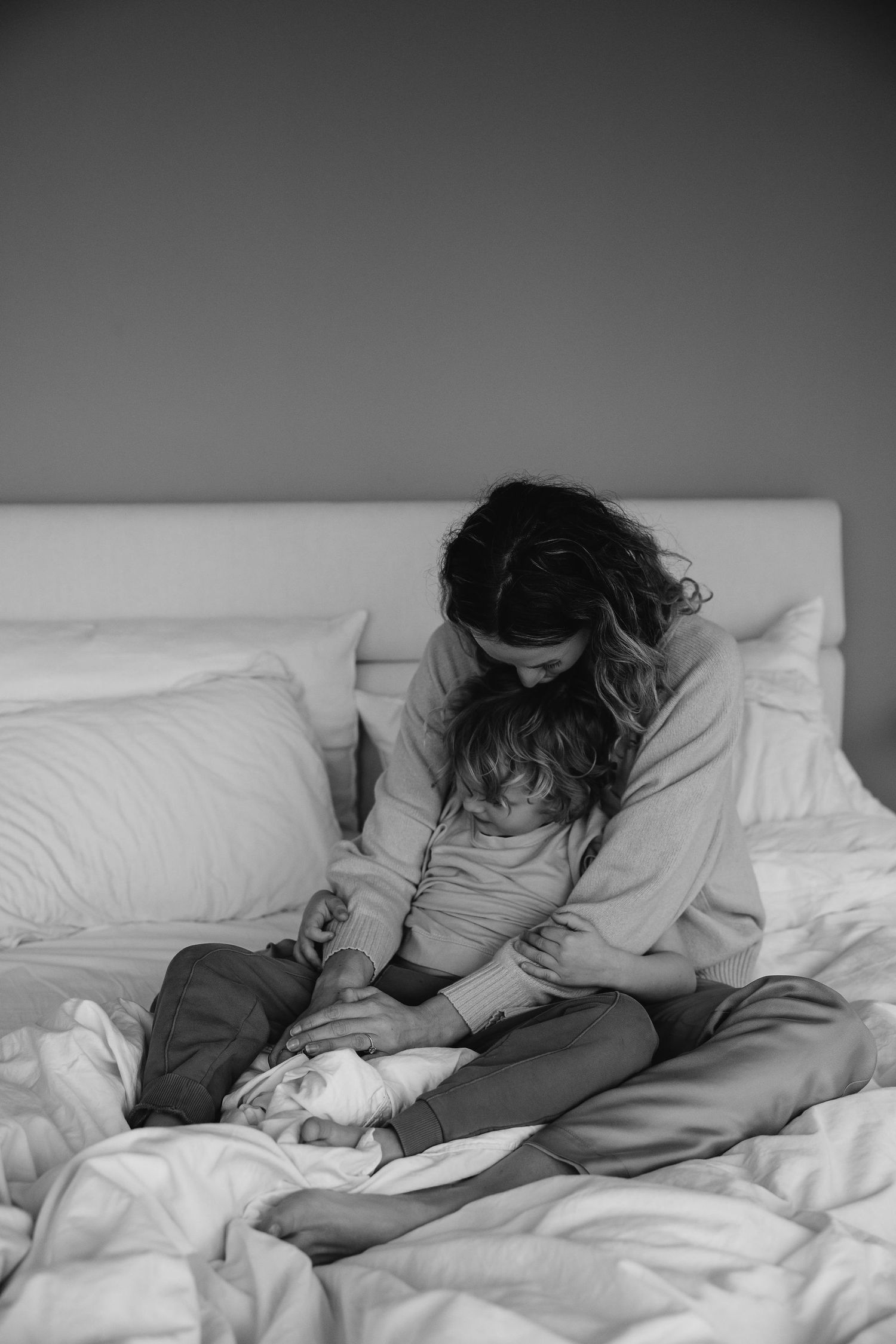 Black and white image of intimate moments shared in bed with soft morning light.