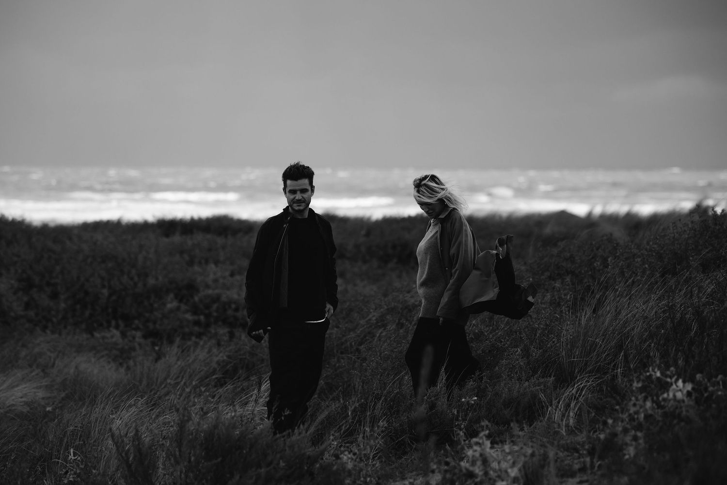Silhouetted figures standing together in an open field at dusk.