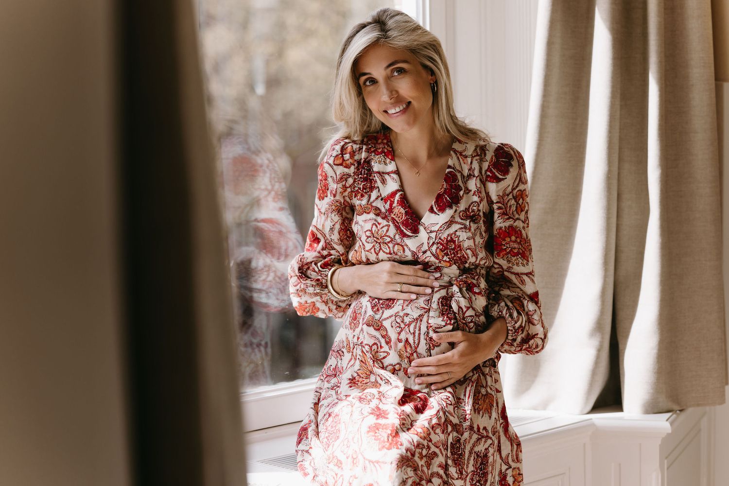 A person in a floral dress poses by a window in a romantic photography series.