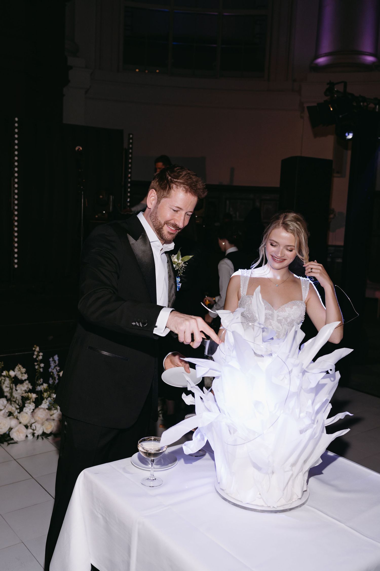 Wedding couple sharing playful moments with sparklers at their reception table.