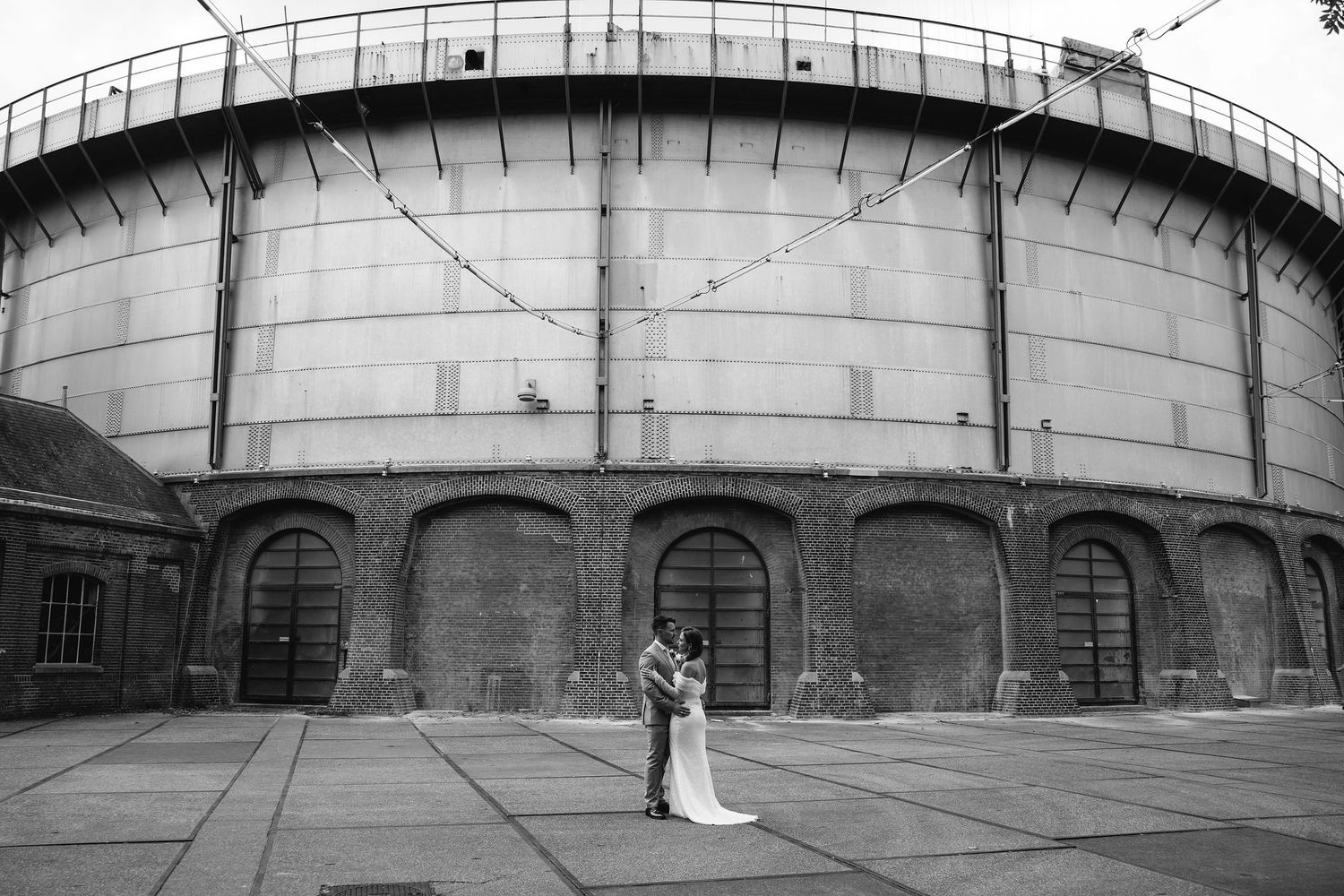Black and white panoramic views of a grand arched brick building facade on a wedding day.