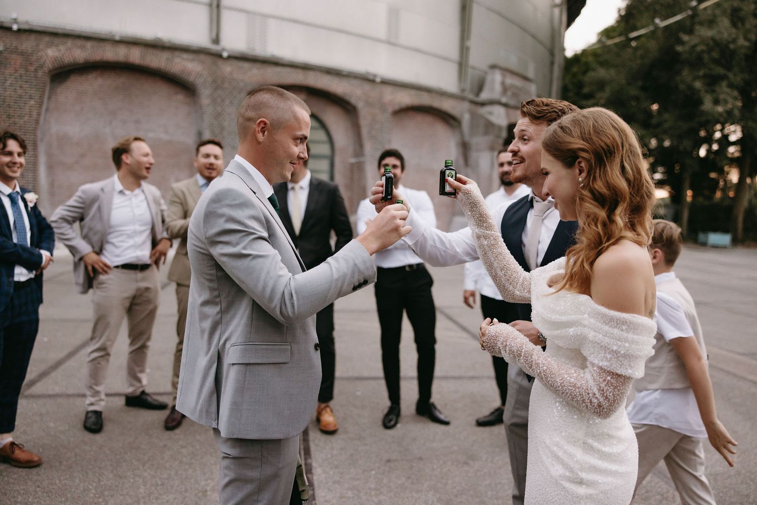 Wedding party jumping and celebrating outdoors in formal attire.