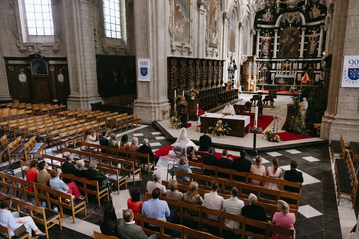 Interior view of a traditional church wedding ceremony with guests seated in wooden pews.
