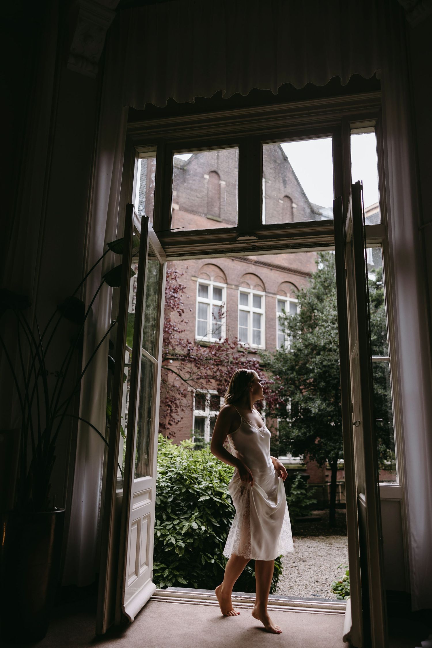 A silhouette of someone standing in a doorway overlooking a courtyard with brick buildings.