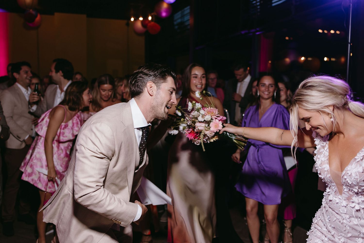 Newlyweds share a playful moment dancing at their reception celebration.