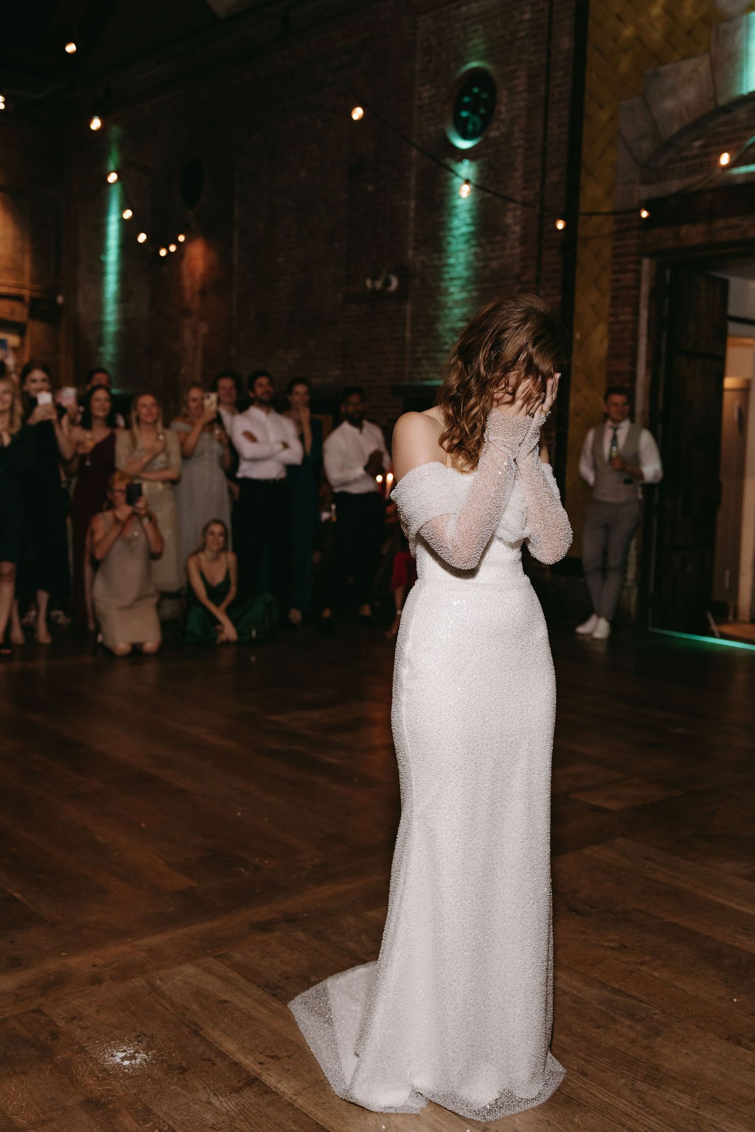 Couples dance across a hardwood floor in an industrial-style venue with green accent lighting.