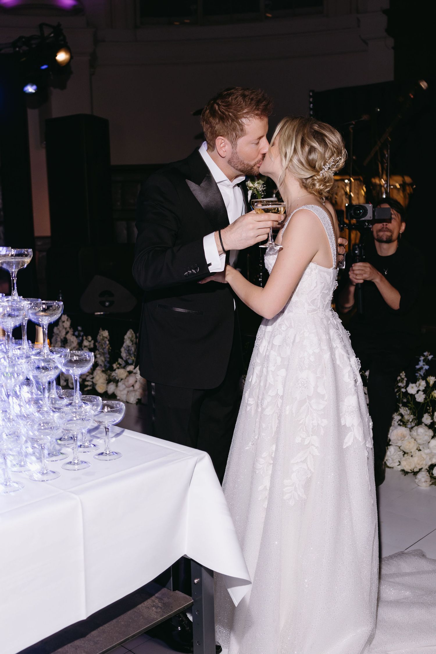 A couple shares an intimate moment near a champagne tower at their wedding reception.