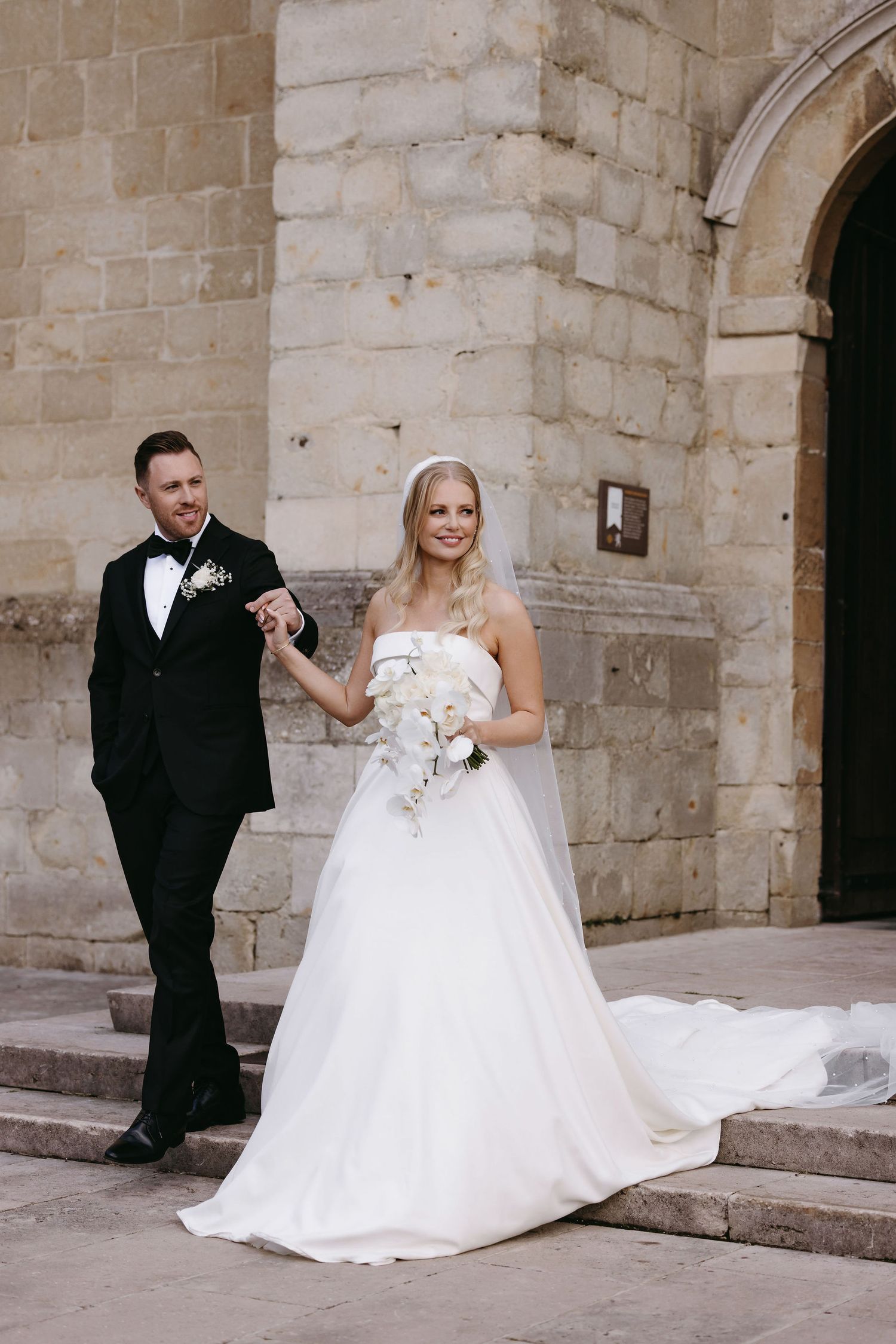 A couple descends stone church steps after their wedding ceremony.