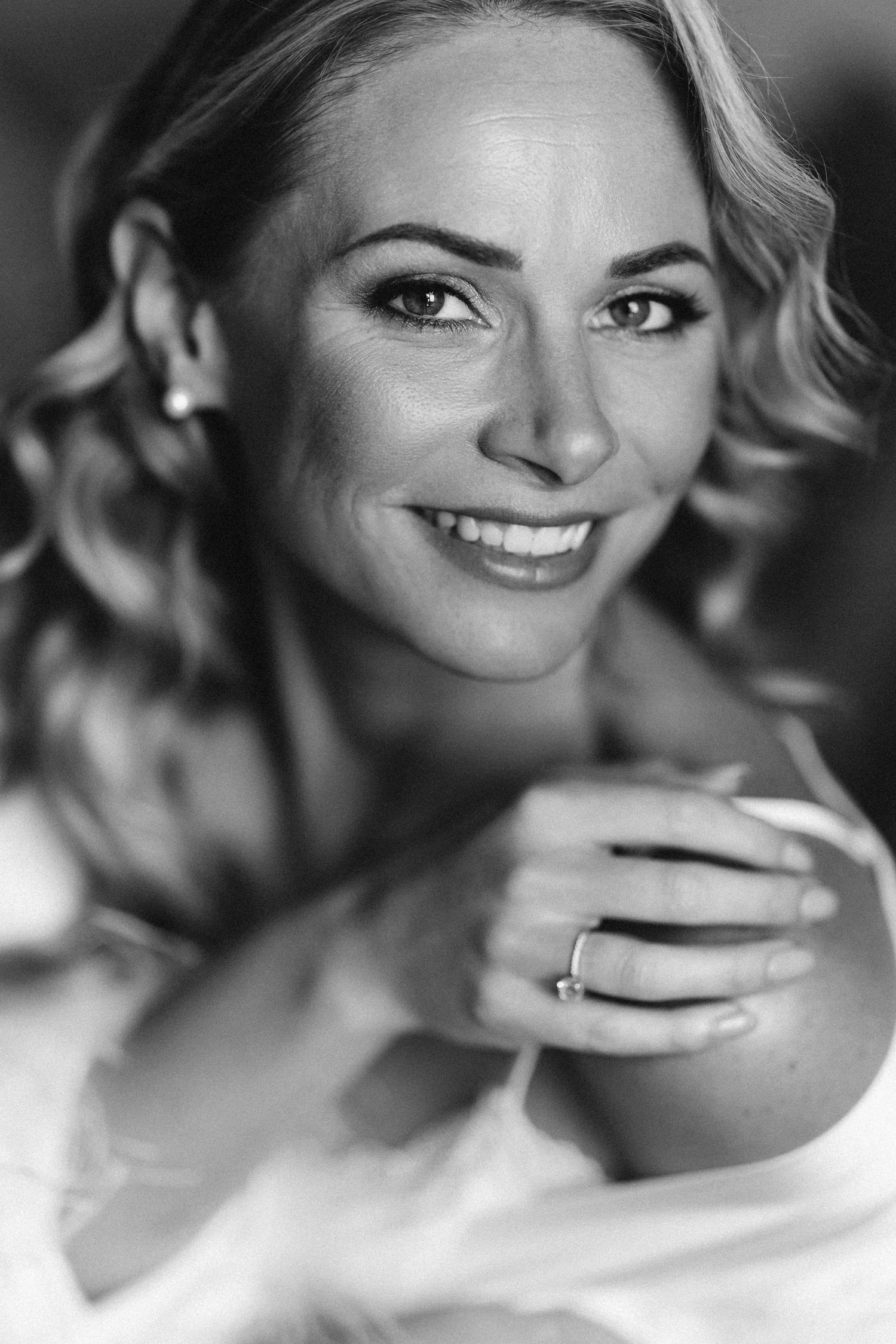 A classic black and white portrait showing a radiant smile and sparkling engagement ring.