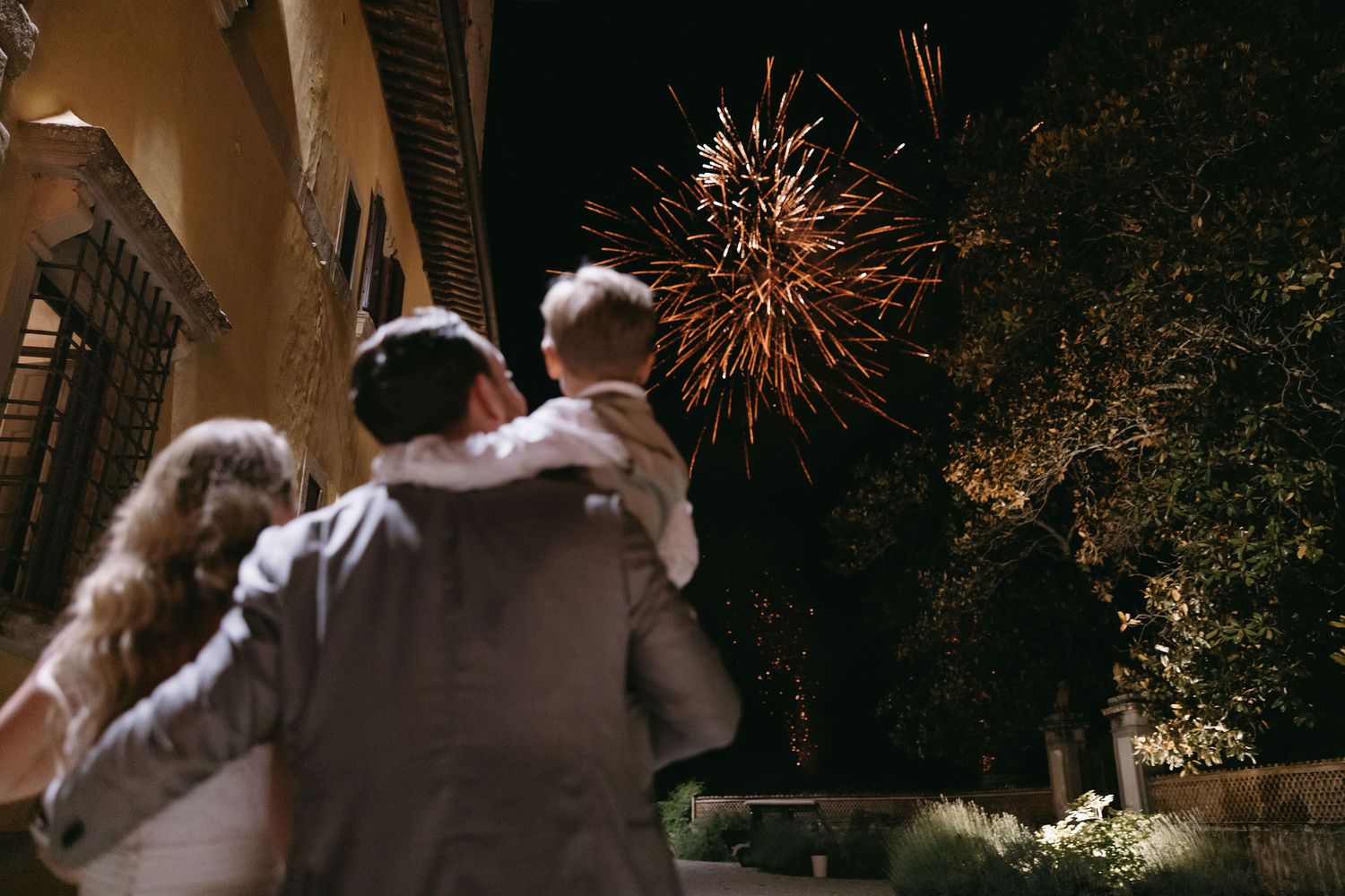 A couple enjoys watching colorful fireworks exploding in the night sky during an outdoor celebration.