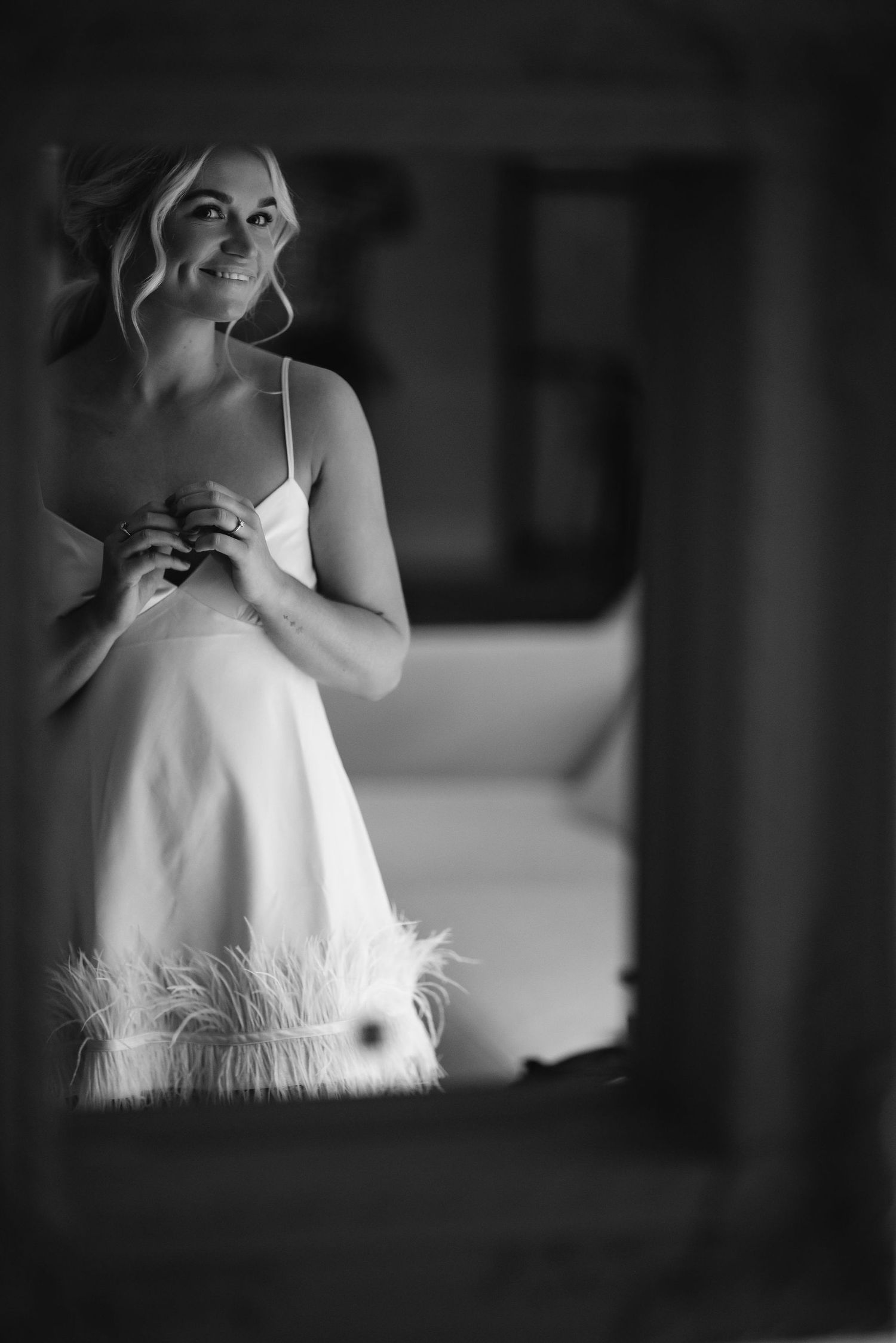 Black and white portrait of someone in a white dress with feather details.
