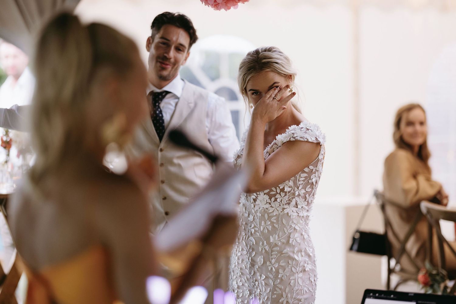 Wedding guests mingling at an outdoor reception with decorative lighting.