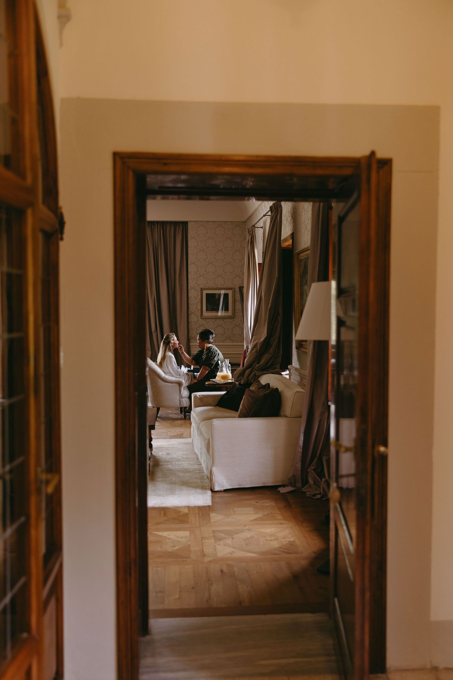 Long hallway with wooden door frames and natural light streaming through multiple doorways.