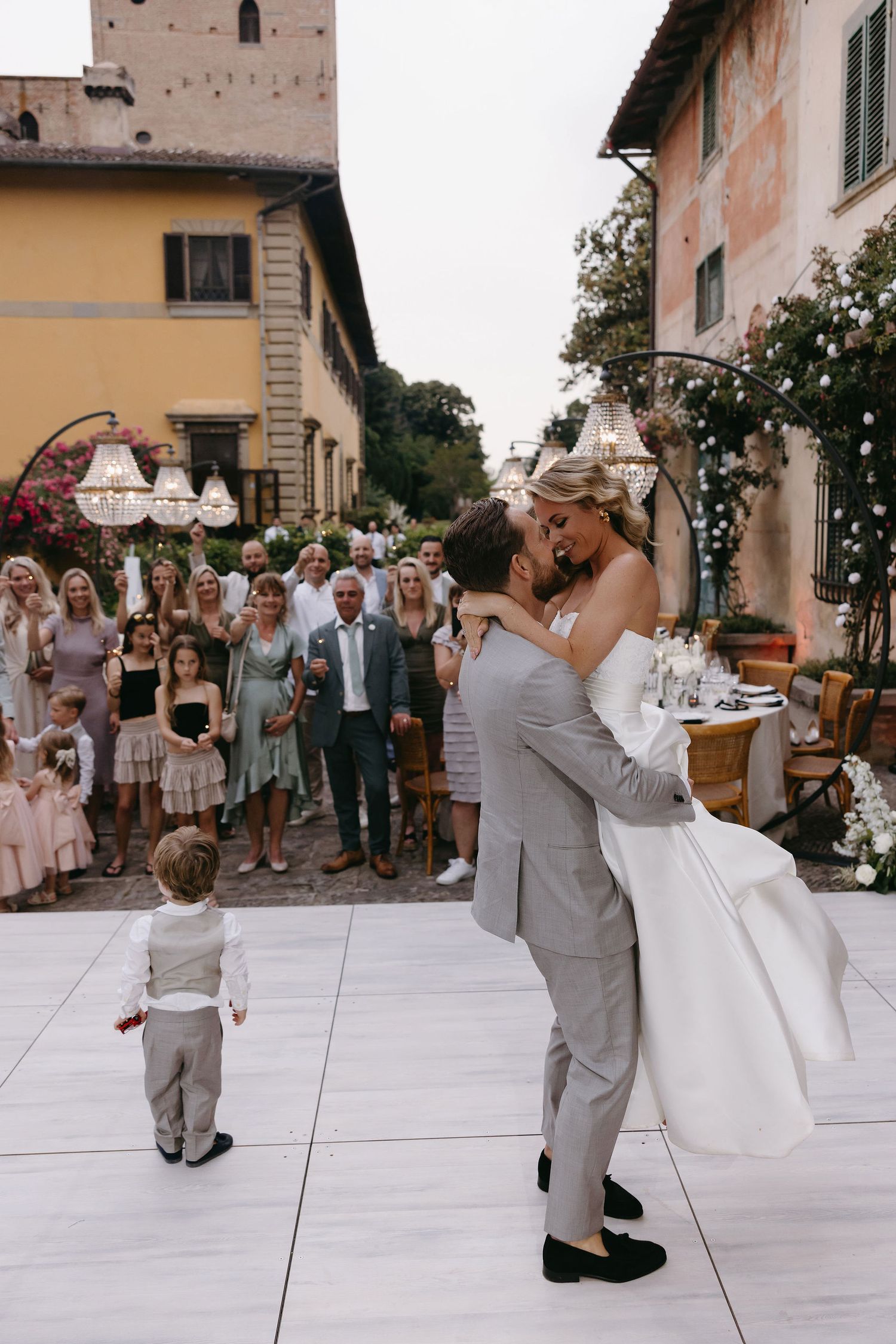 Wedding couple dancing with guests on outdoor patio during Italian villa reception.