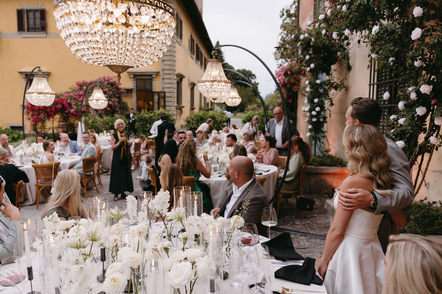 Elegant wedding reception setup with crystal chandeliers and formal table settings.