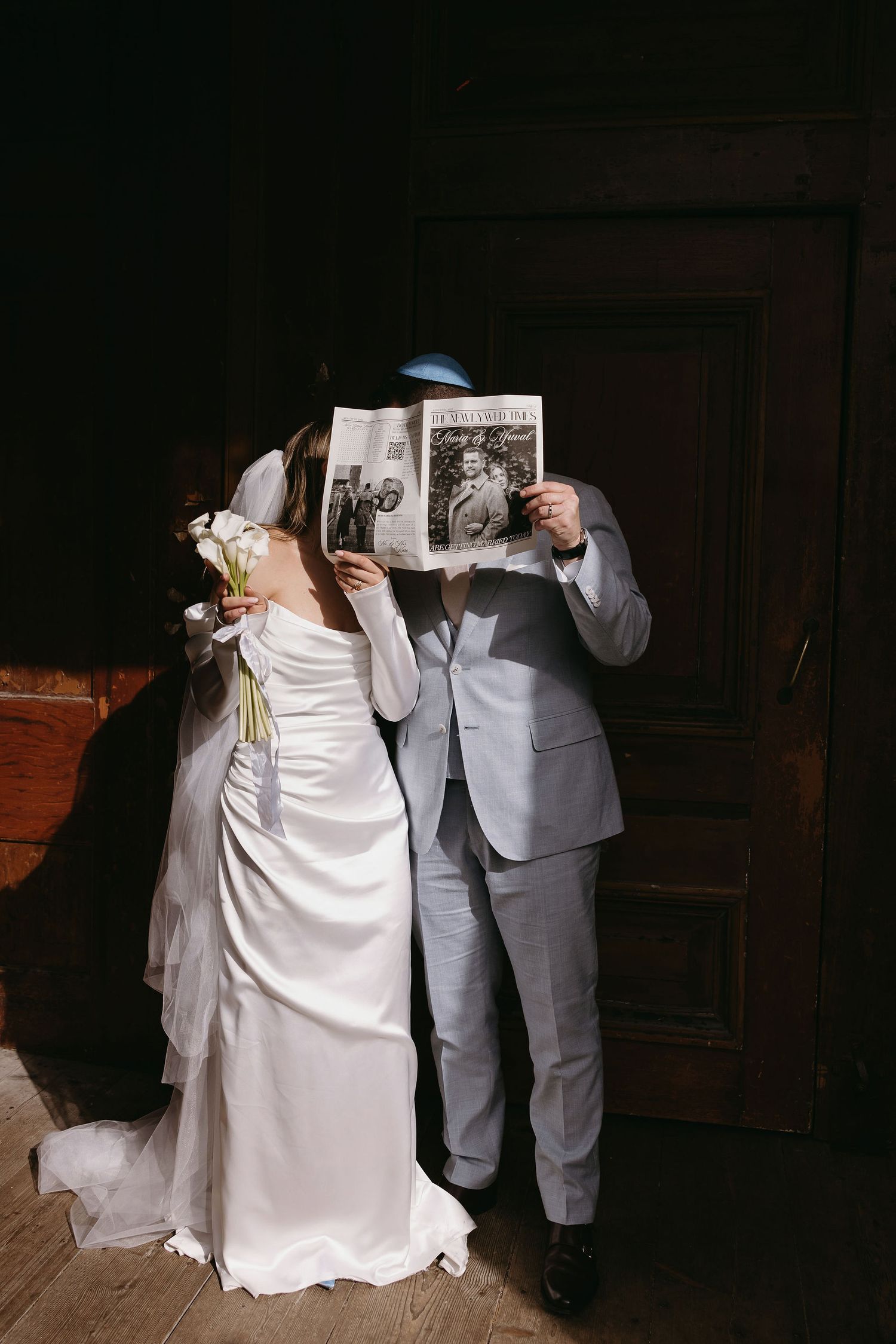 Couple in wedding attire dancing together in dimly lit room.