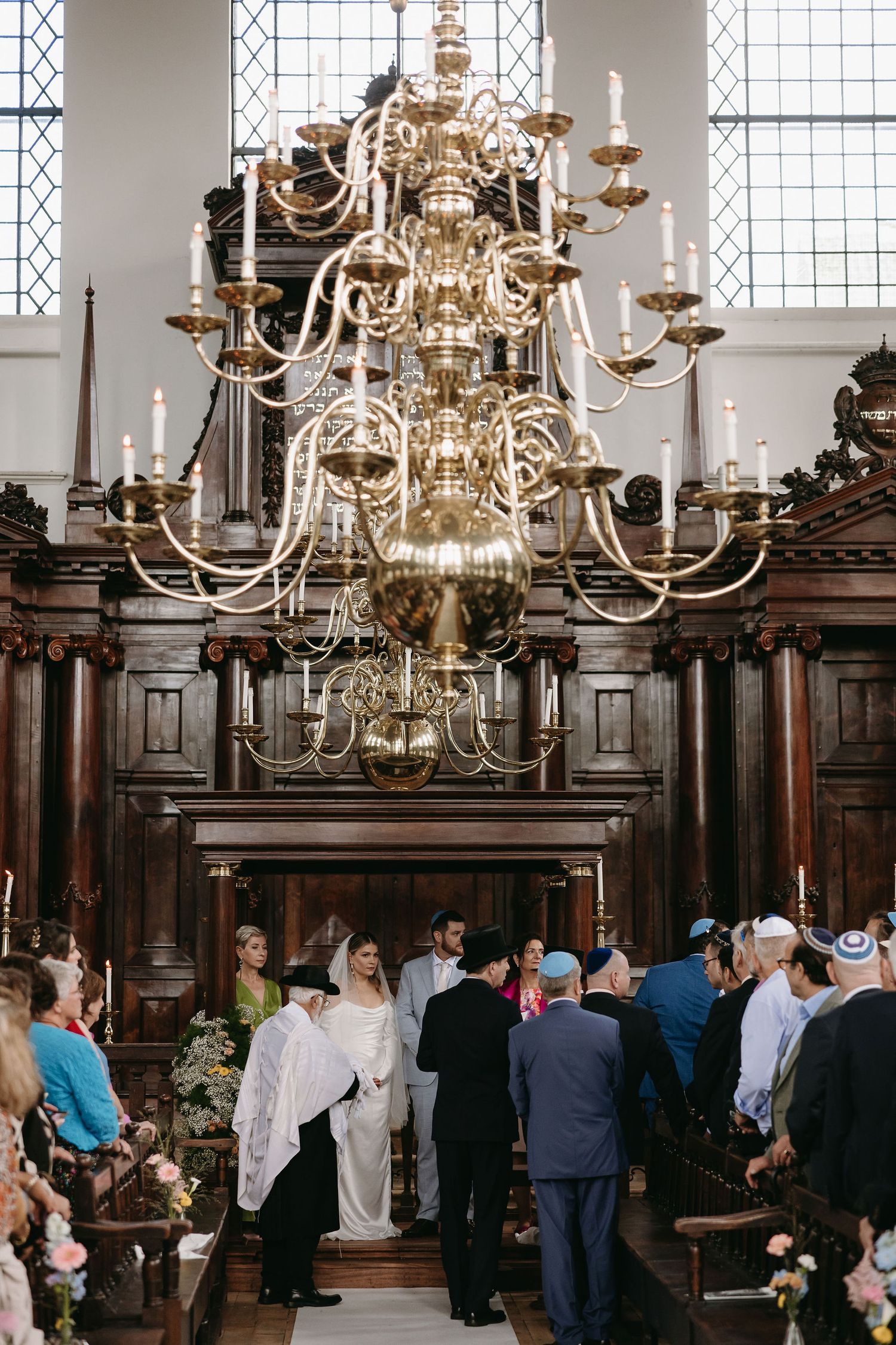 Church interior with elegant golden chandeliers and gathered guests for a wedding ceremony.
