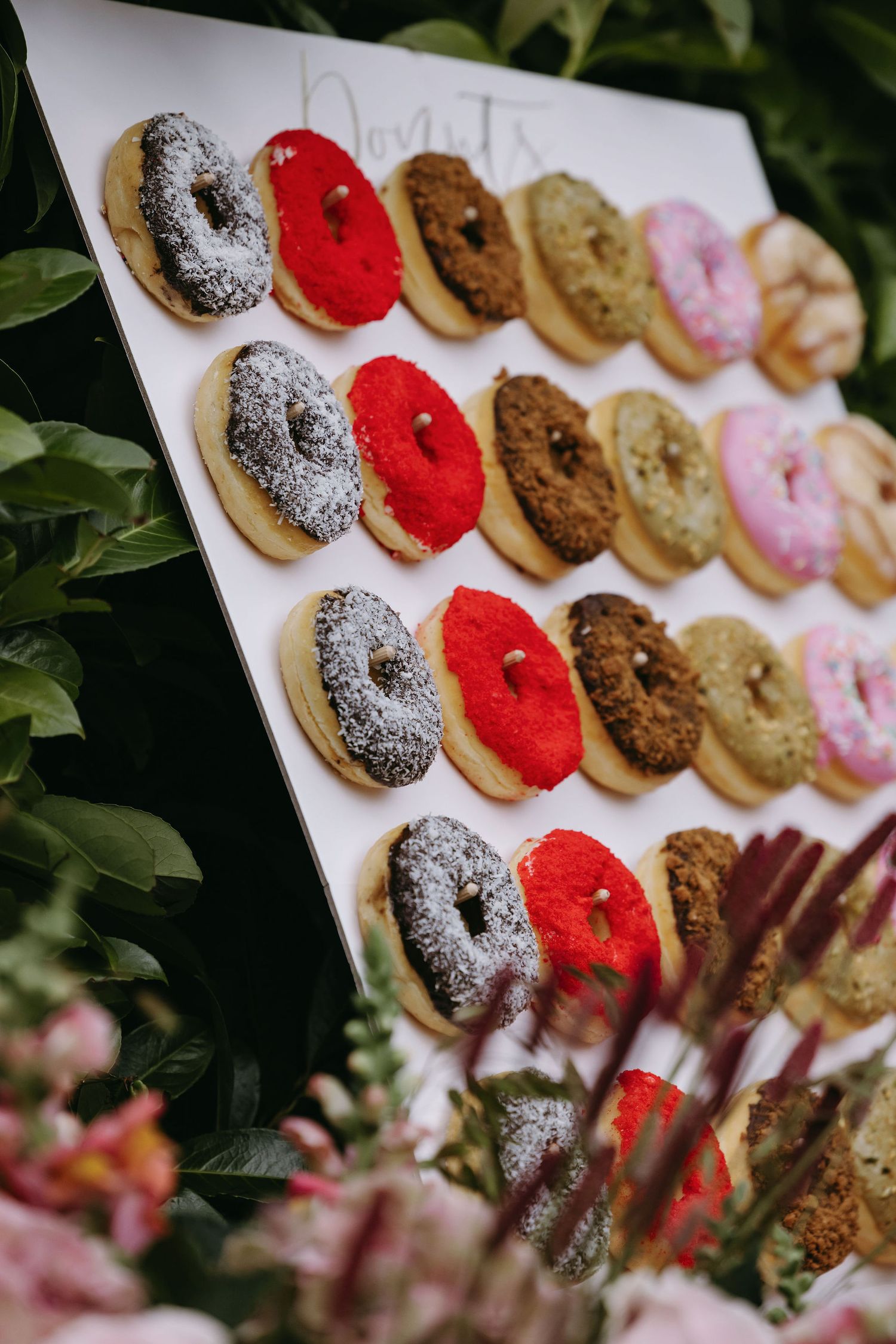 Colorful assortment of decorated donuts displayed on white platter.