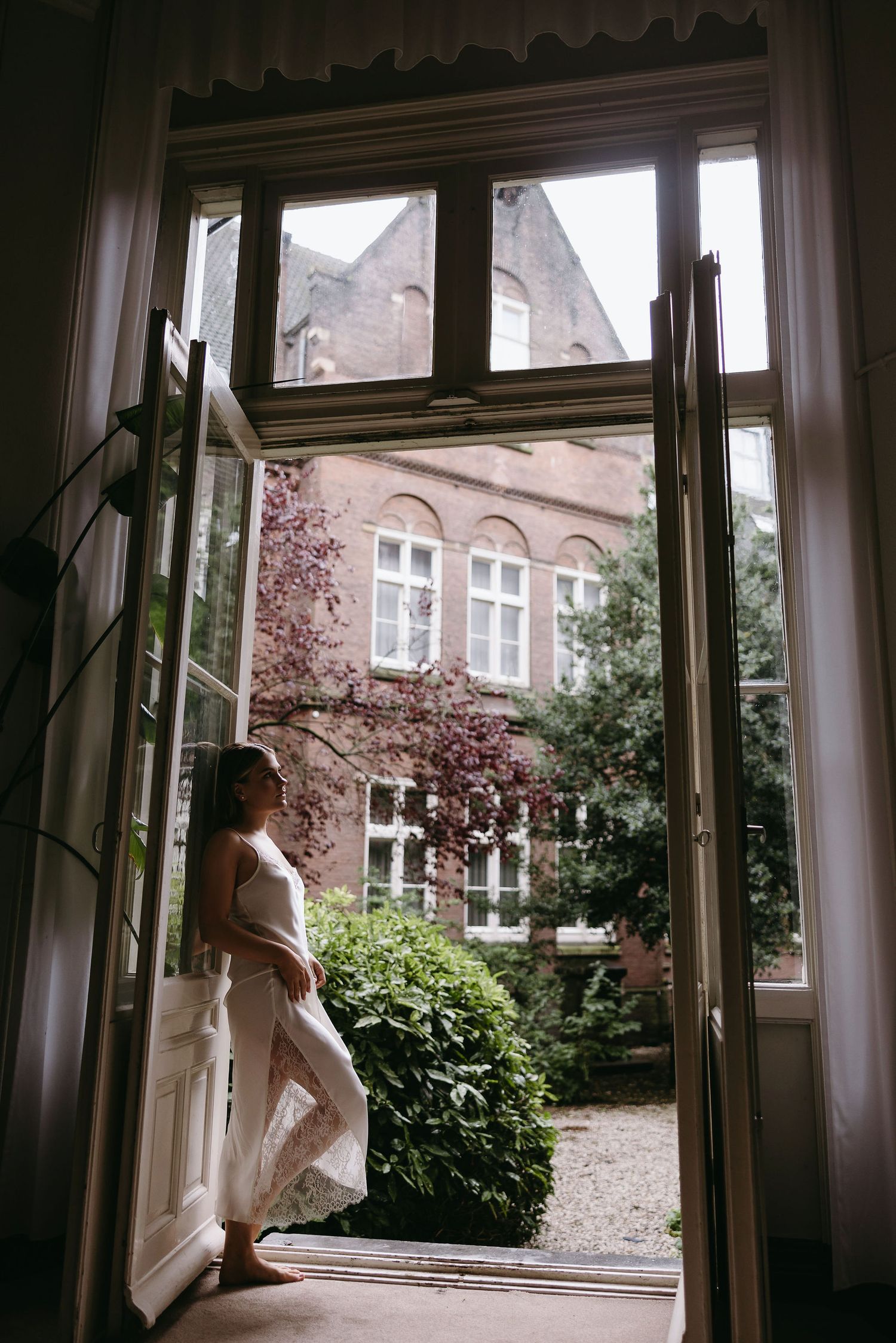 View through window panes showing a garden and historic brick building exterior.