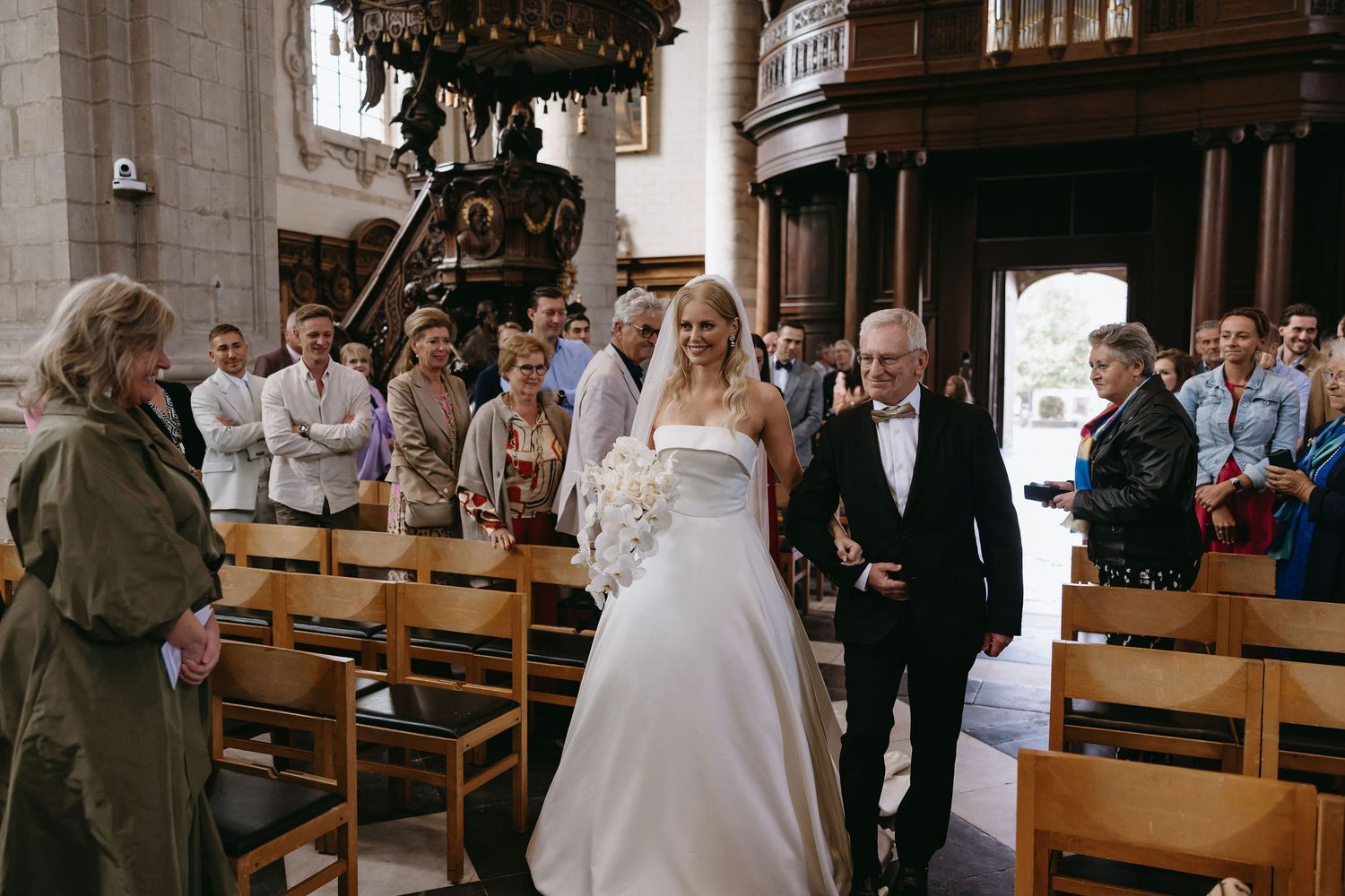 Wedding ceremony in a traditional church with wooden pews and guests watching the proceedings.