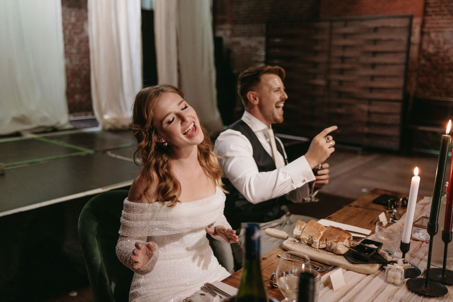 Couple enjoying dinner at their wedding reception with exposed brick wall decor.