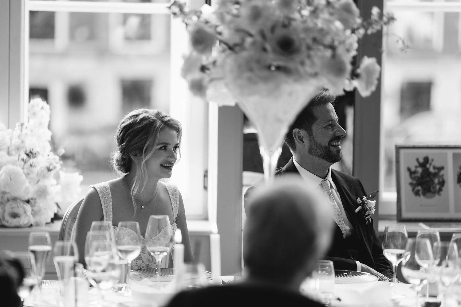 Reception table setting with elegant floral arrangements and natural window light.