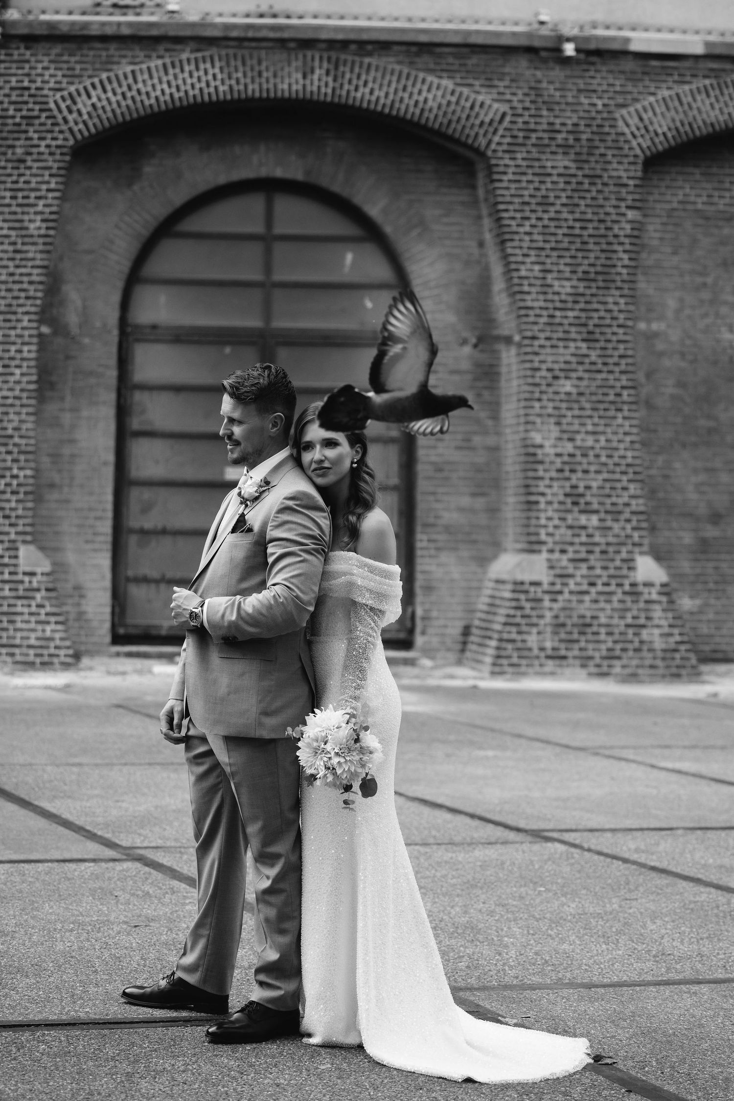 Black and white wedding photos outside a brick building with elegant archways.