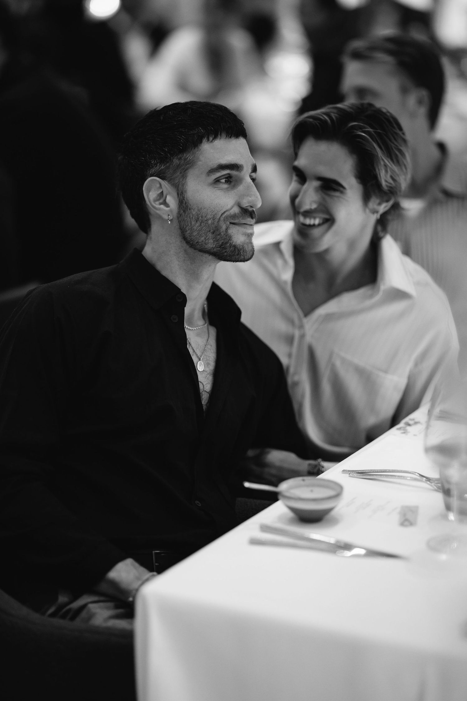 Two guests enjoying conversation at an elegant dinner table in black and white.