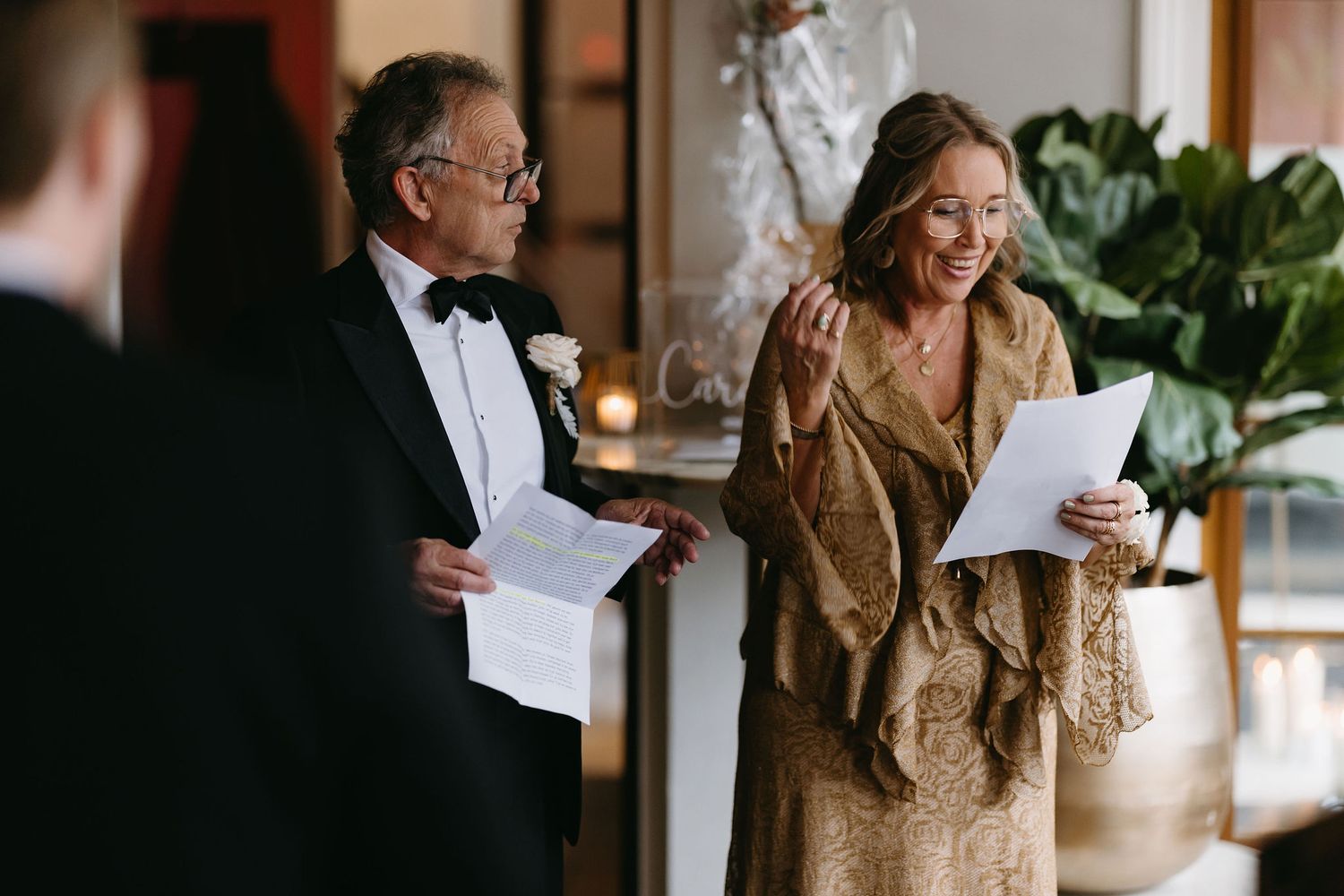 Two people in formal attire reading documents together during what appears to be a wedding ceremony.