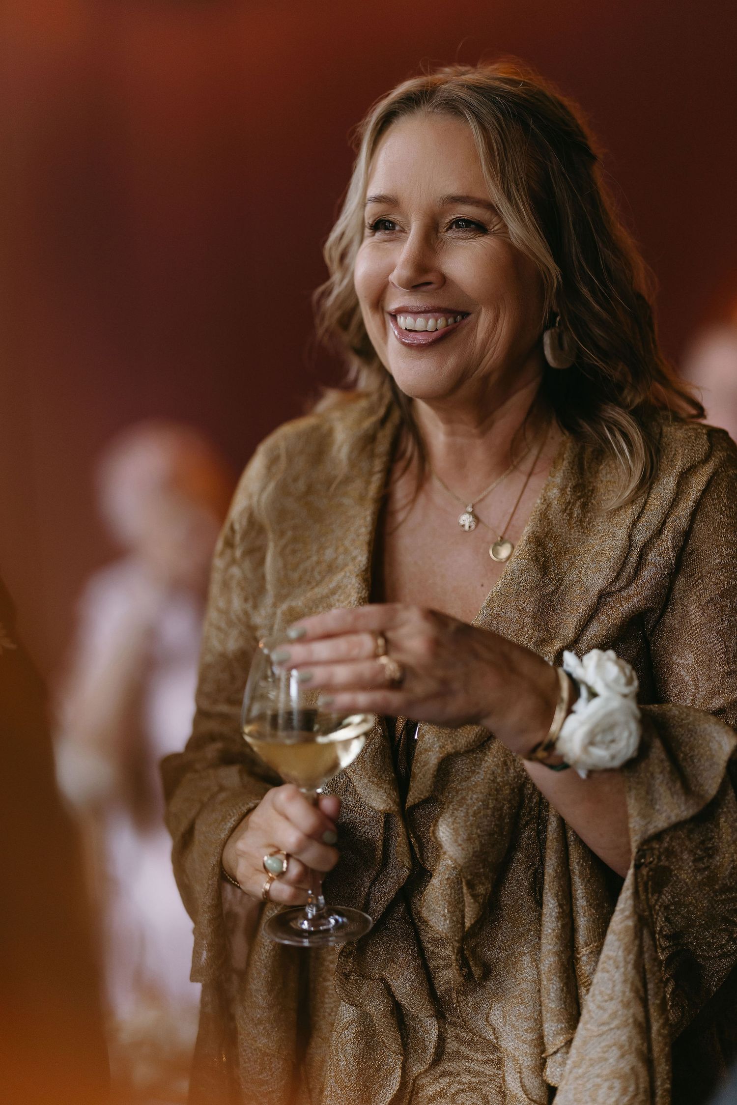 Guest enjoys a glass of wine while wearing a cozy brown shawl at an evening event.