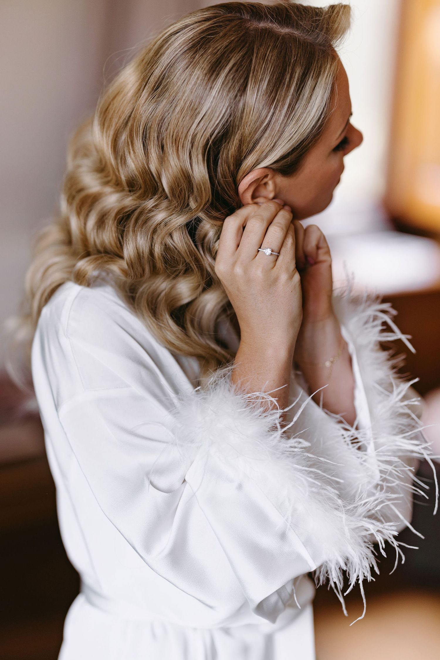 Close up of bridal hairstyle with glamorous vintage waves and feather robe.