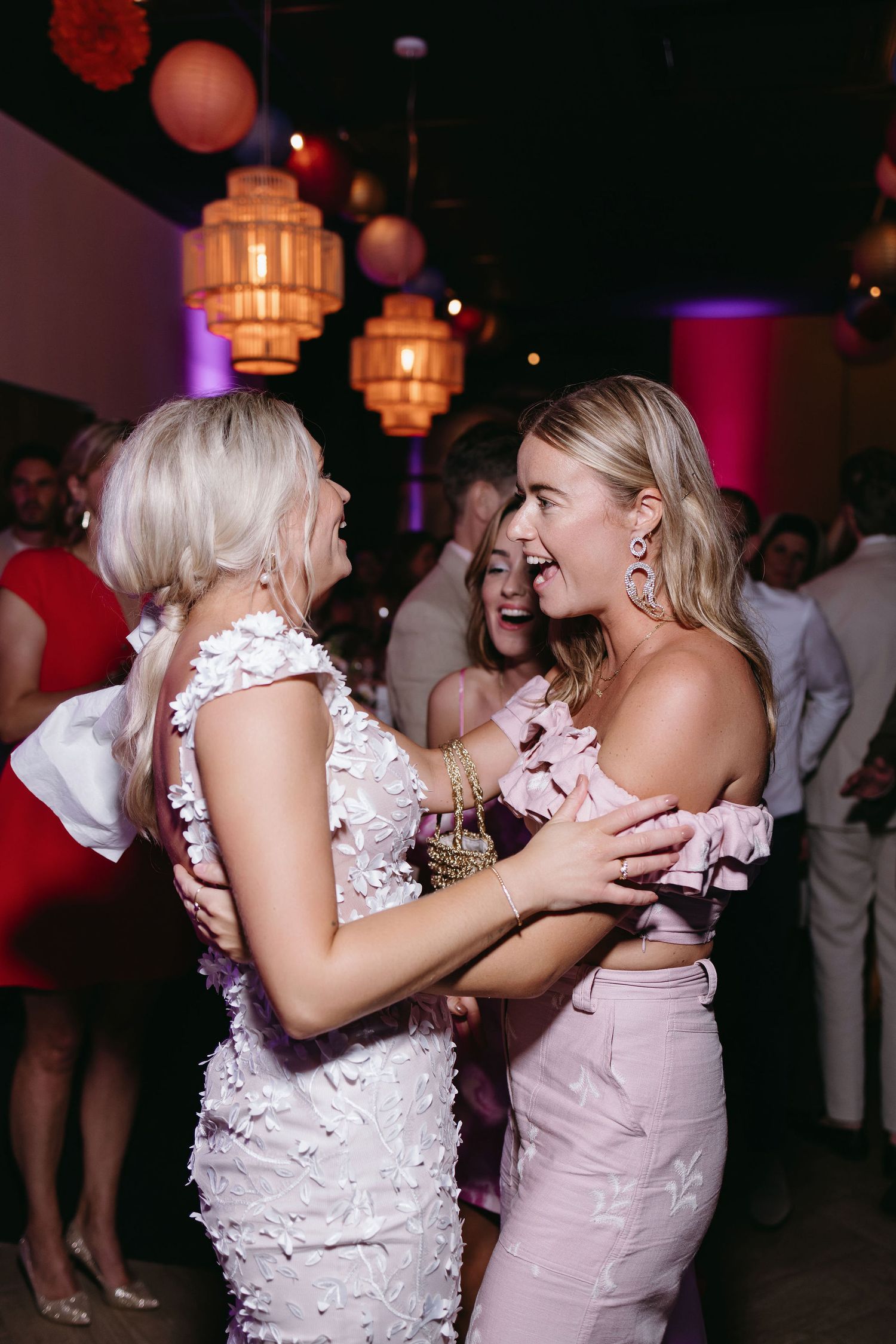 Two people share an emotional moment on dance floor under ambient lighting at reception.