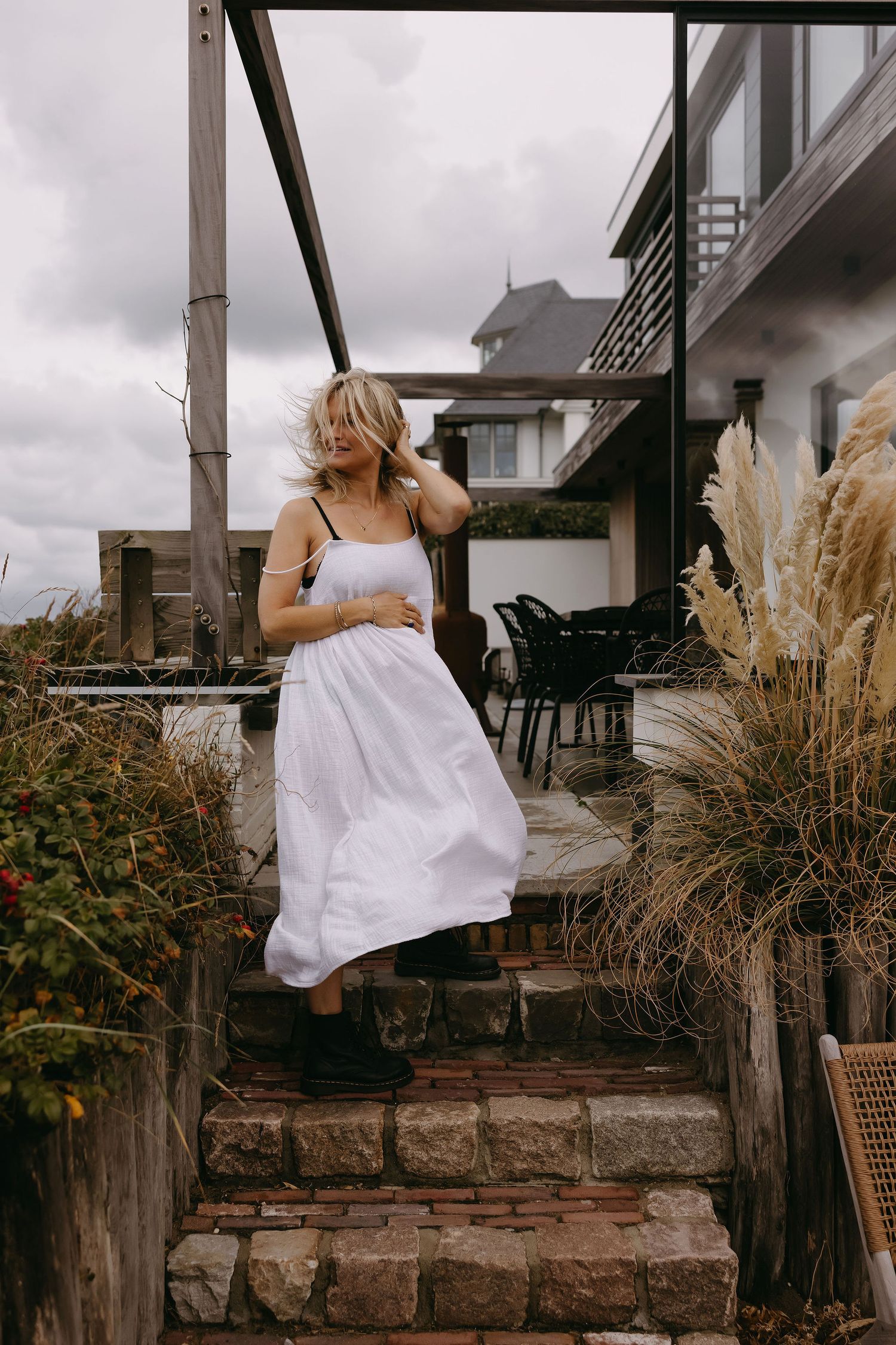 Outdoor maternity session on patio with decorative grasses and white flowing dress.
