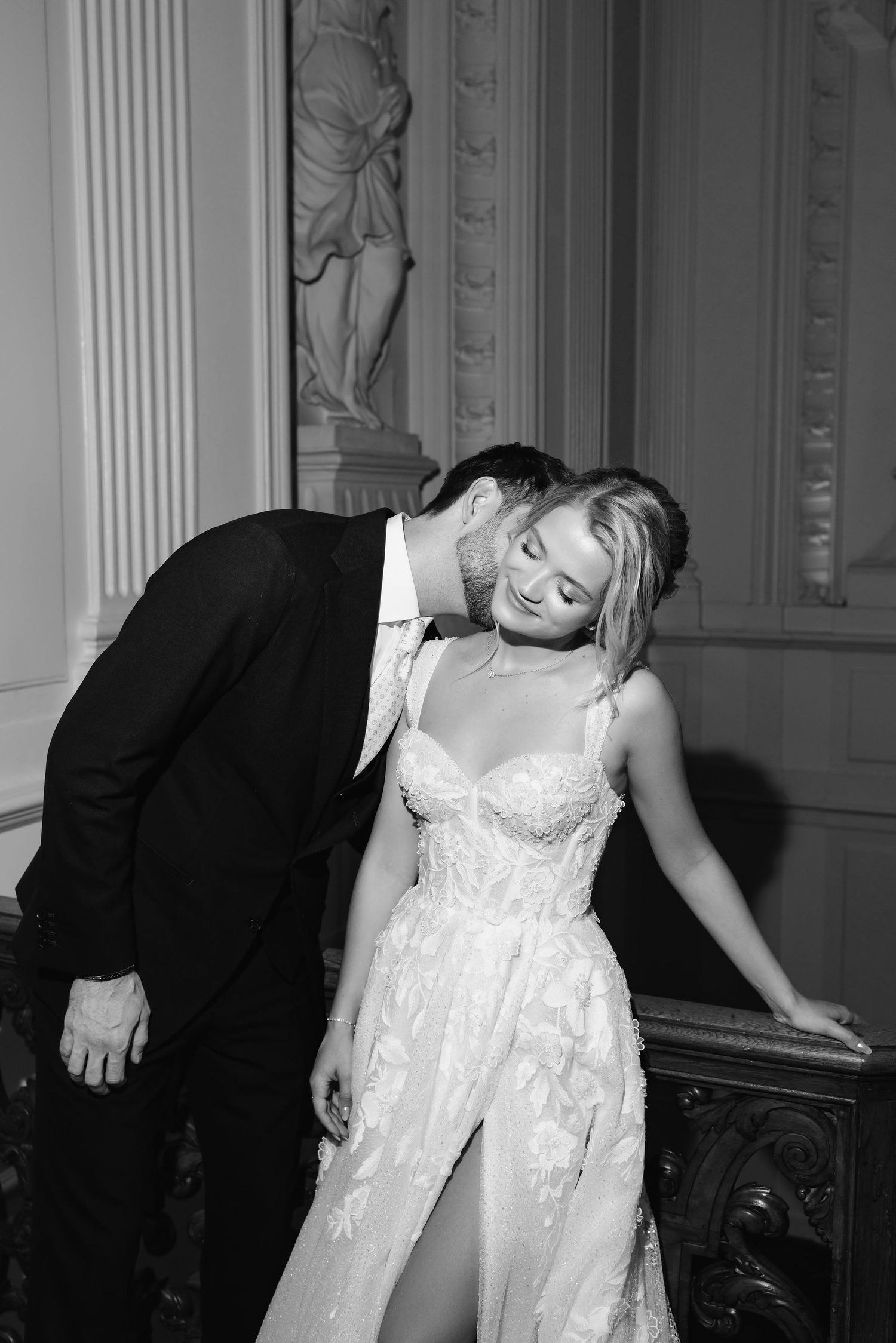 Dramatic black and white sequence of a couple in wedding attire sharing playful moments against ornate pillars.