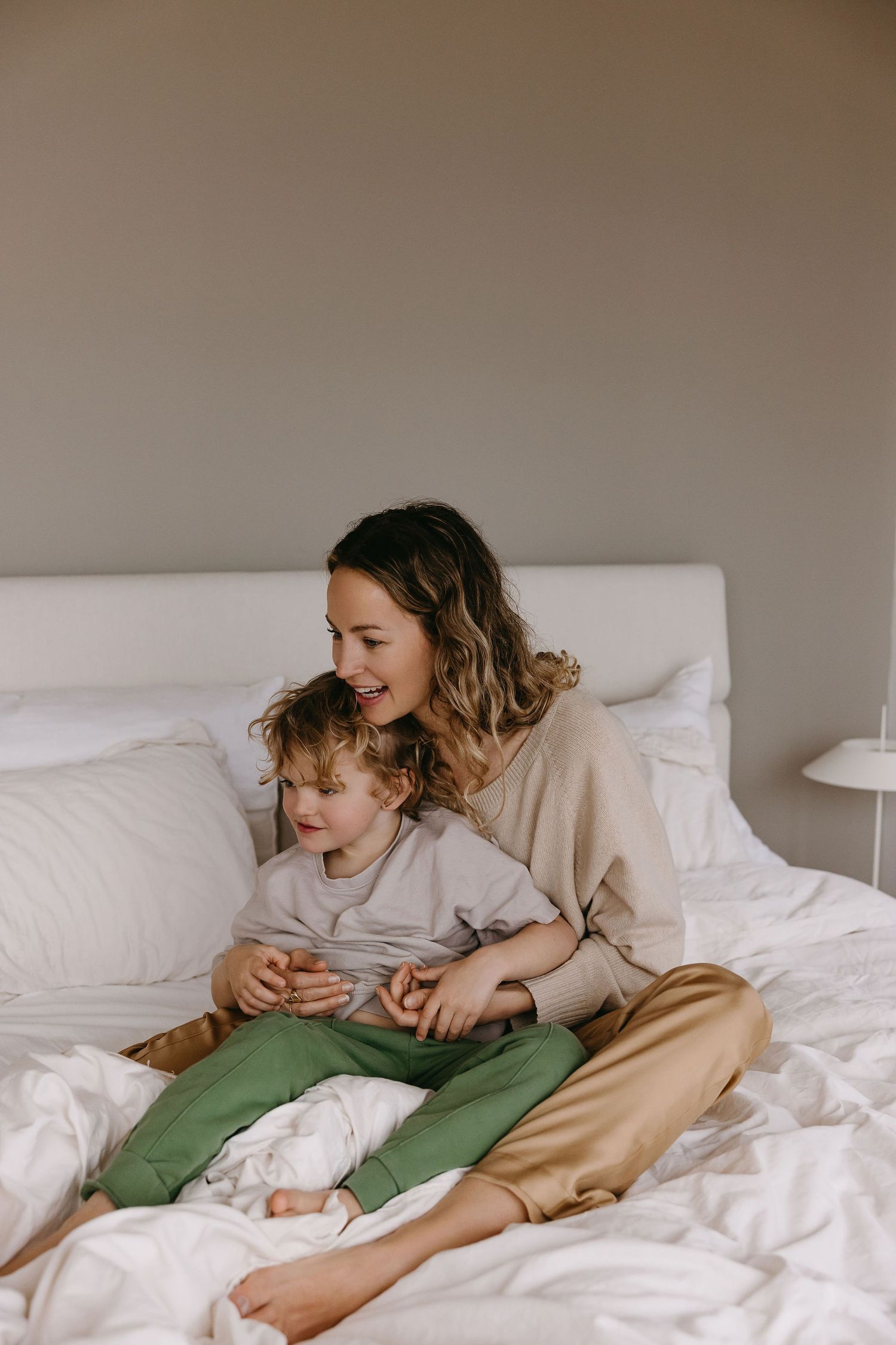 Gentle morning moments shared between family members on white bedding.