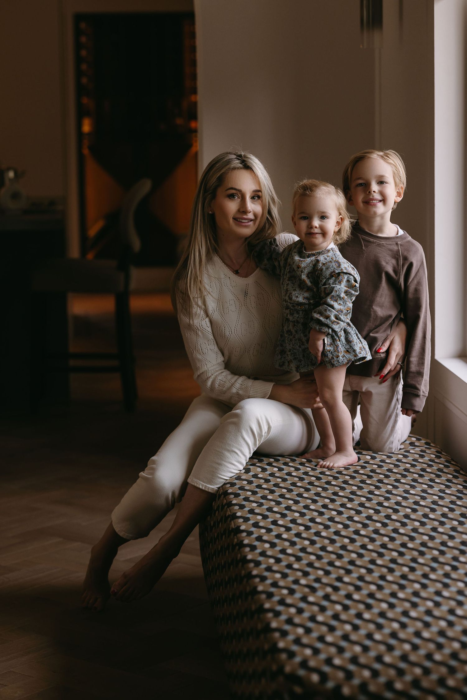 Intimate family portrait by window on geometric patterned furniture.