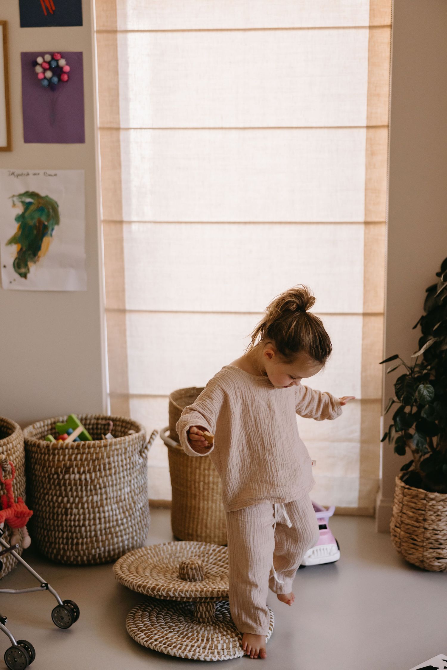 Woven baskets sit near a window while someone in white arranges items in a bright, minimalist room.