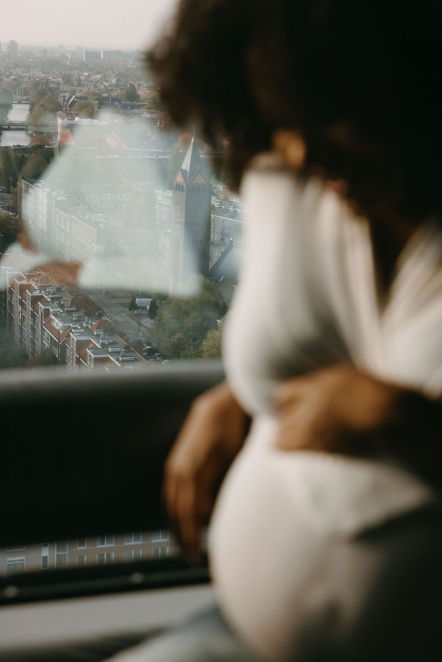 View of a cityscape through a window with someone sitting in silhouette.