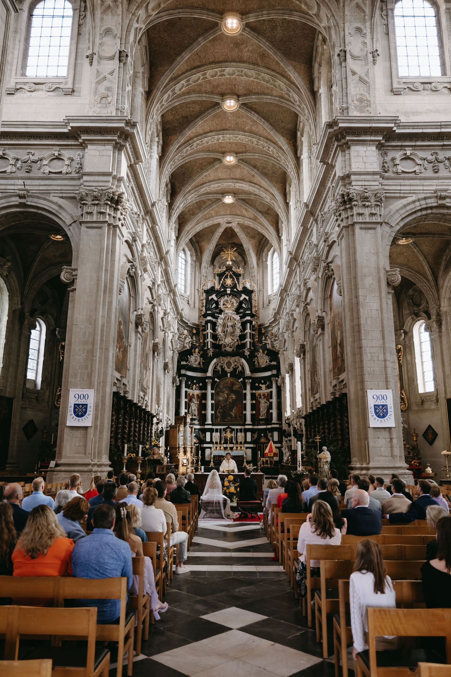 Wedding ceremony in ornate cathedral with vaulted ceilings and elaborate altar.