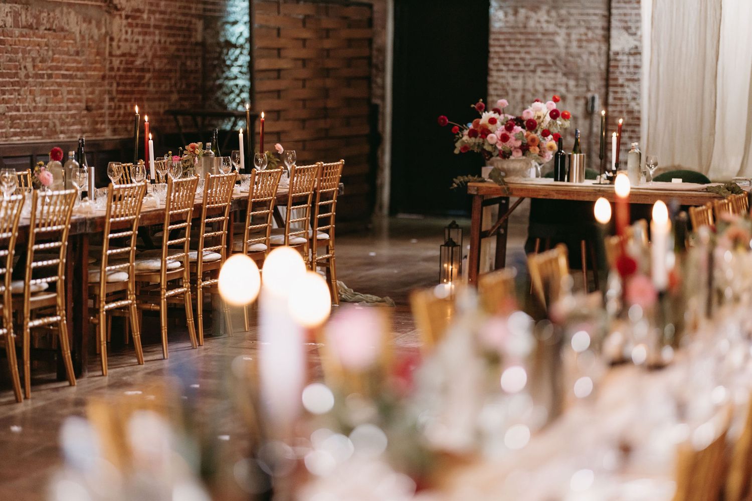 Rustic wedding reception setup with wooden tables, candlelight, and floral centerpieces.