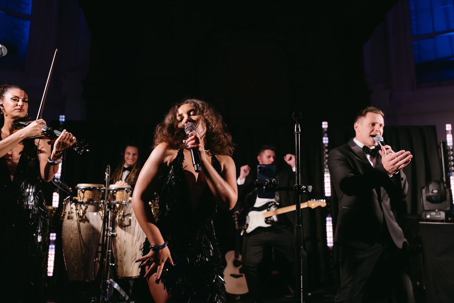 Wedding reception dance party with band performing in dark atmospheric lighting.
