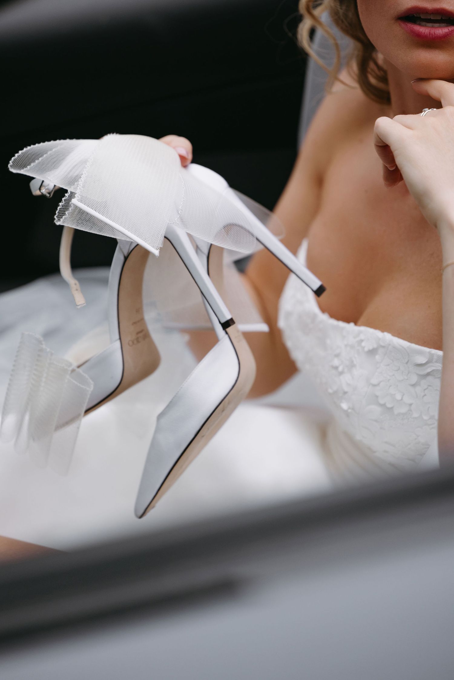 Elegant white bridal shoes with delicate bow details captured in an artistic close-up shot.