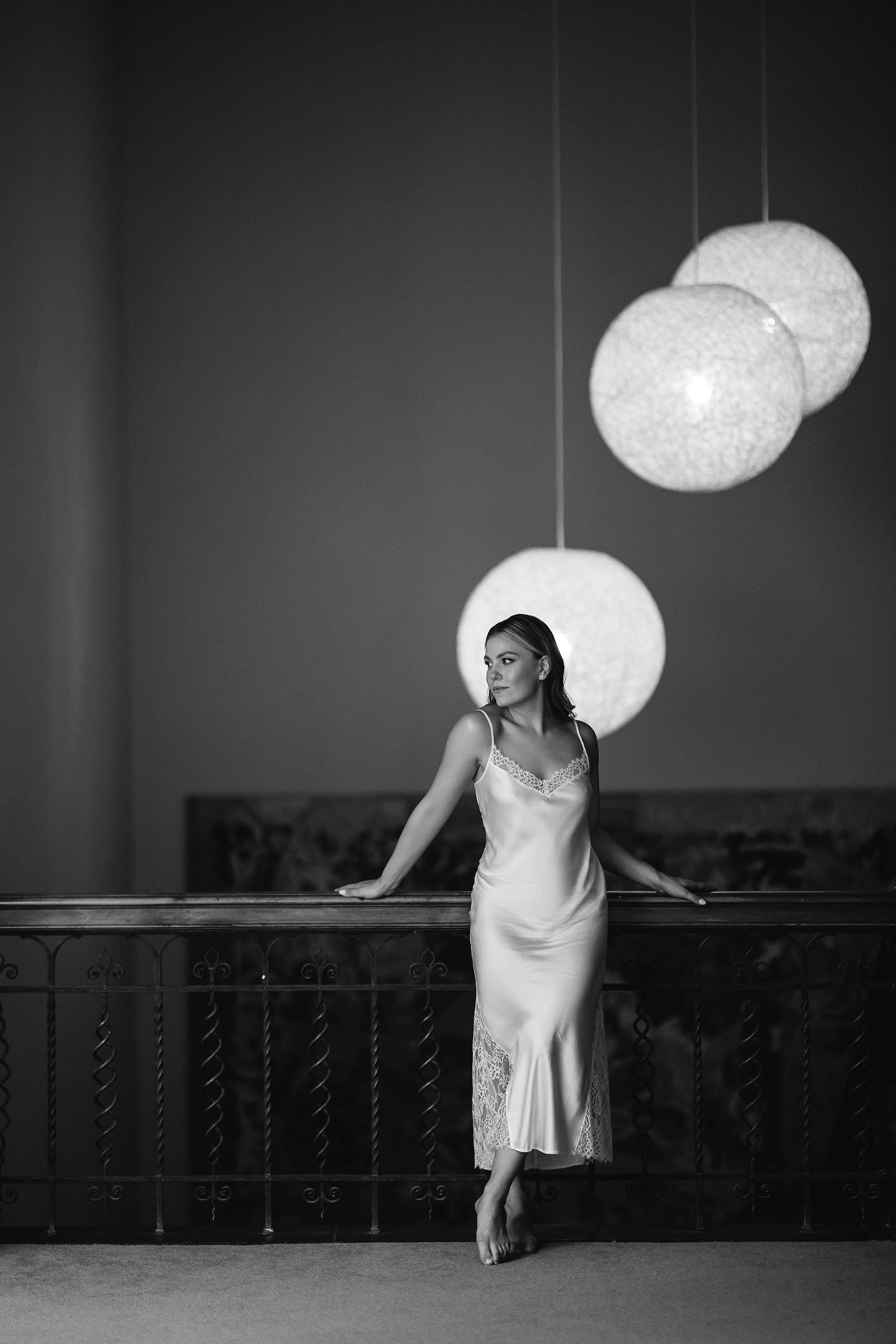 Artistic black and white portrait with hanging sphere lights creating dramatic ambiance.