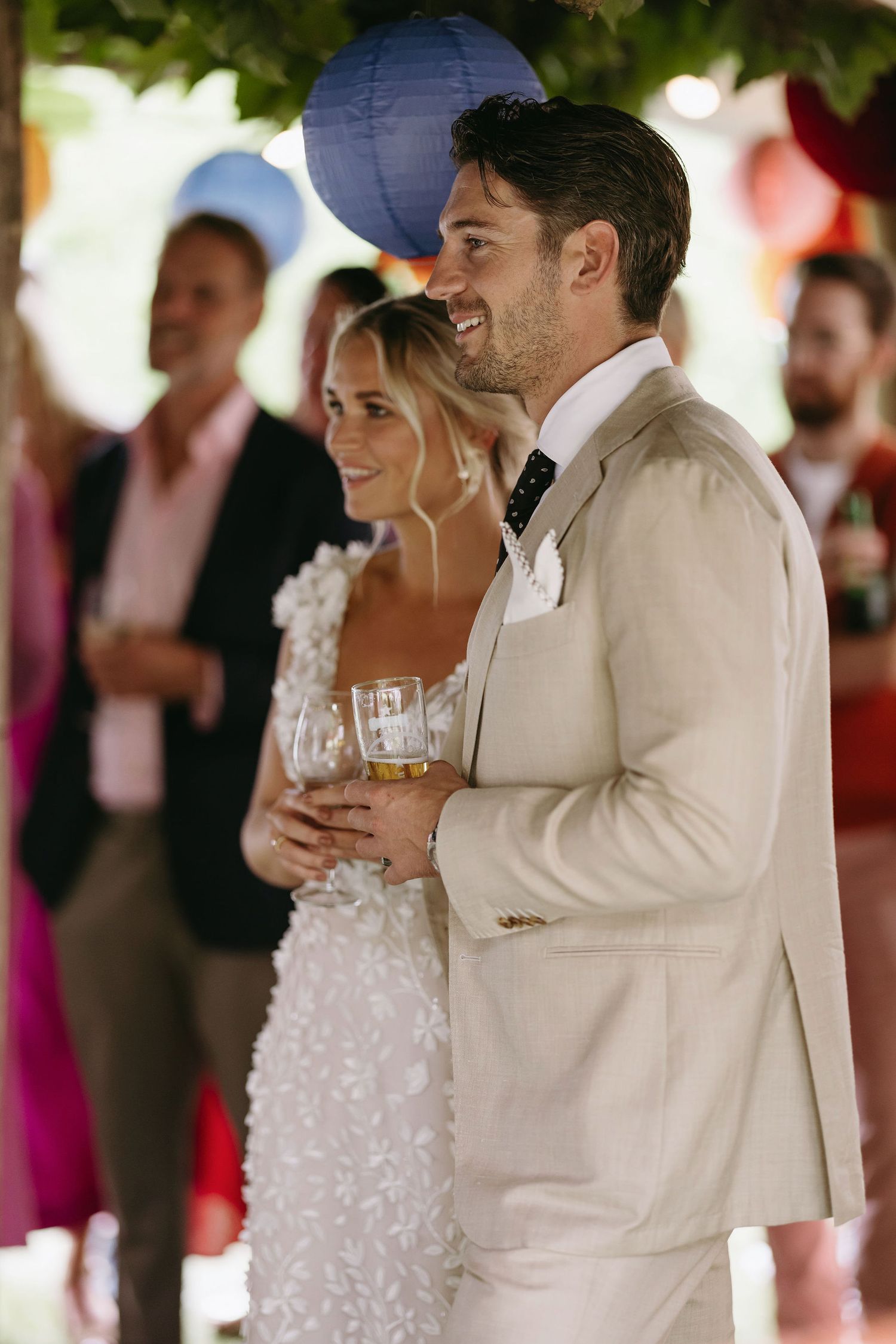 Newlyweds share an intimate moment during their reception under blue paper lanterns.