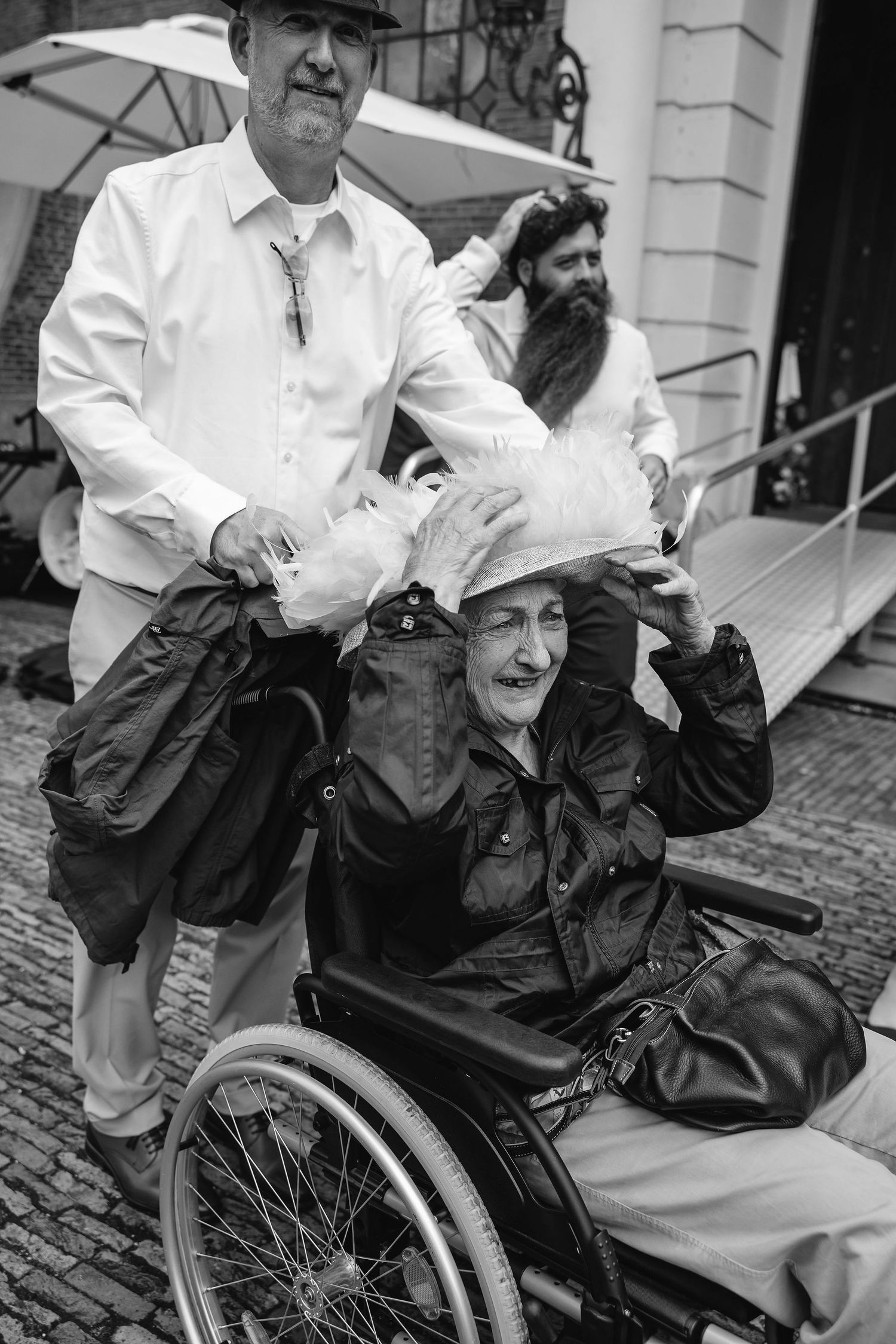 Black and white photo of people assisting someone in a wheelchair during an outdoor event.