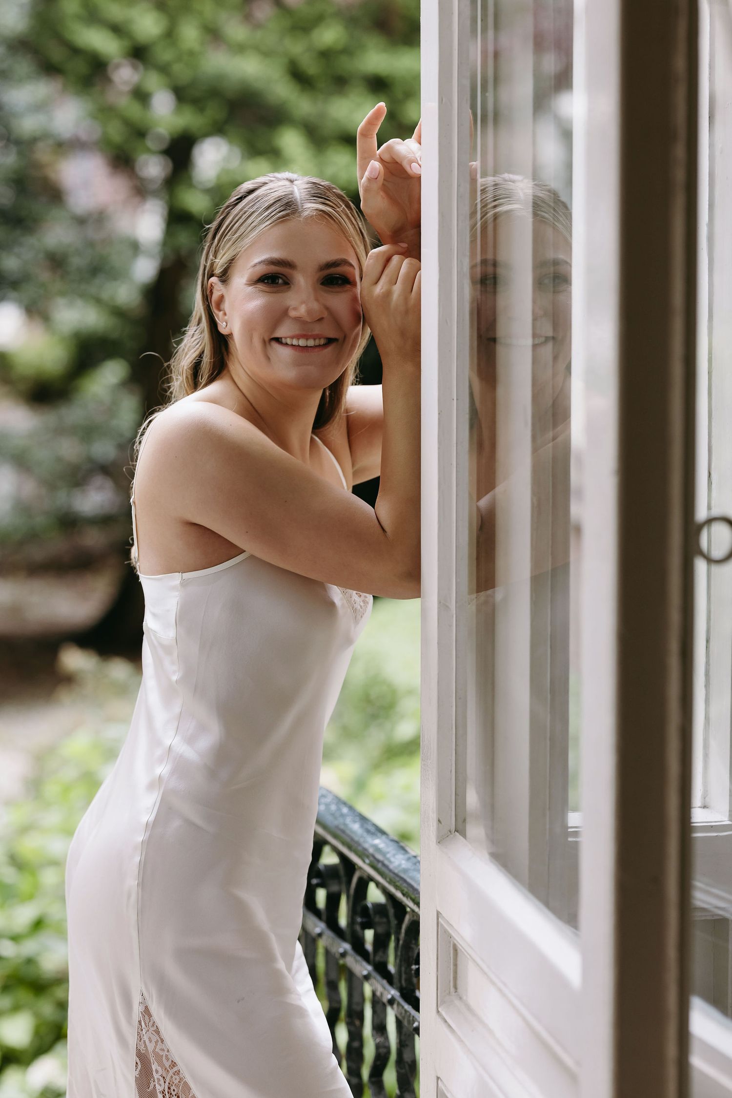 A bride in a white dress looking through a window.