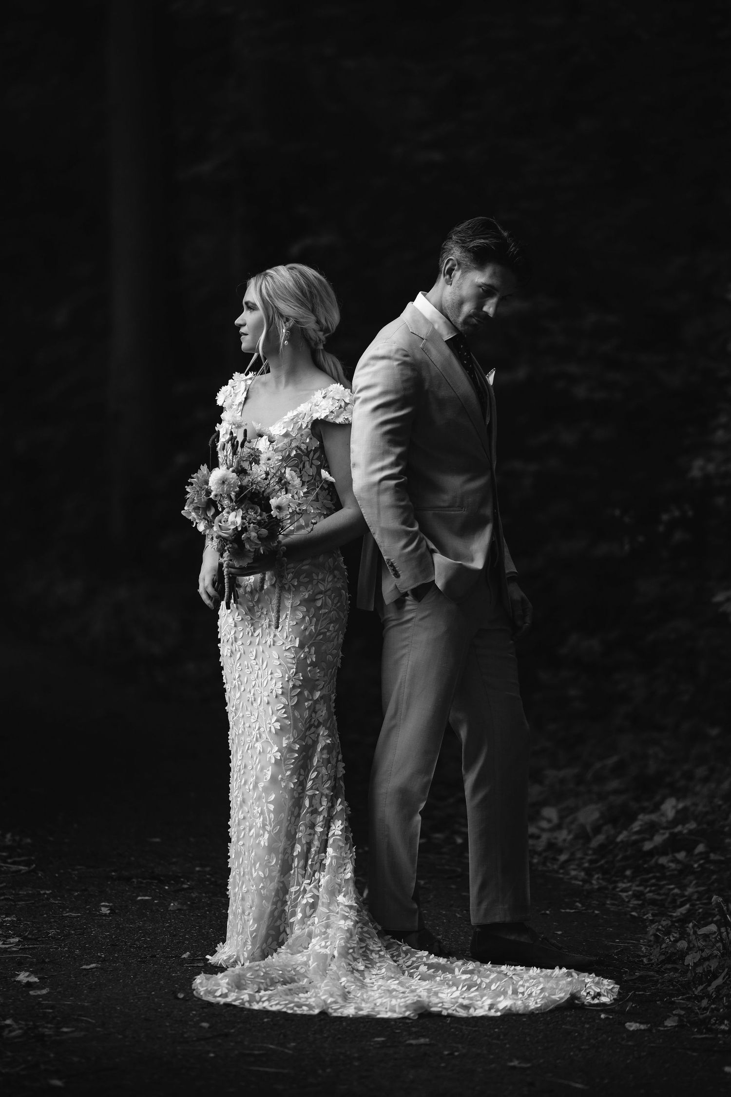 Artistic black and white portrait of wedding couple standing back to back.