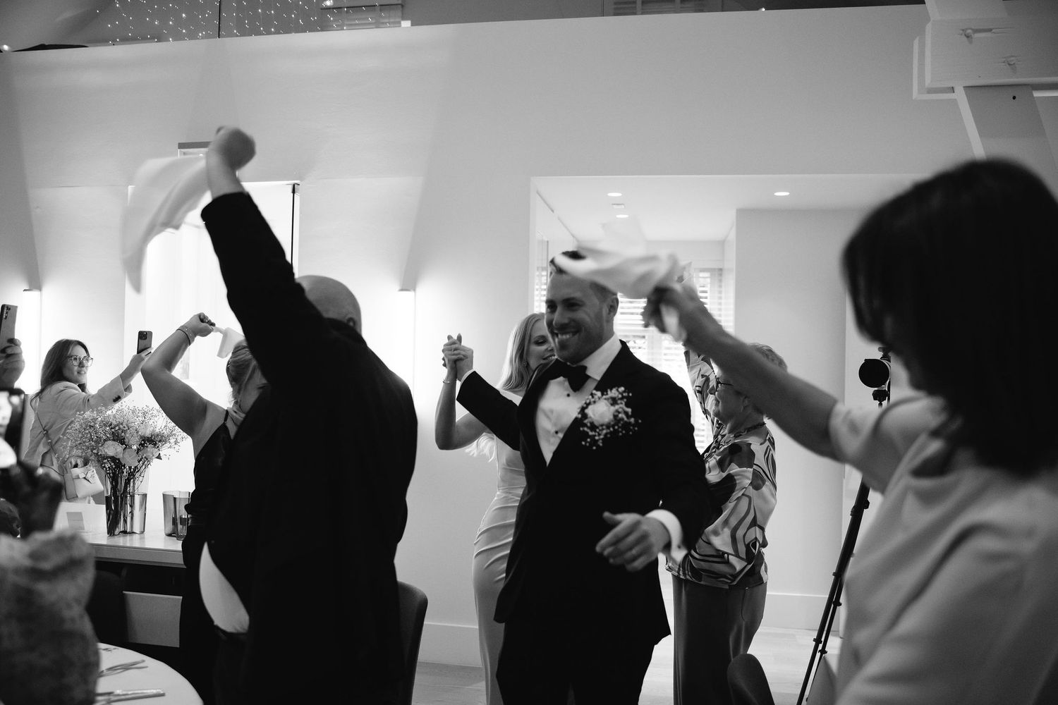 Wedding guests dancing and celebrating at reception in black and white photography.