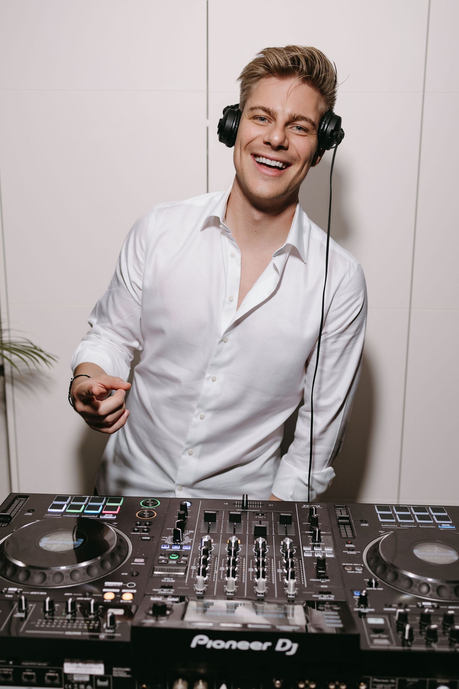 DJ plays music from professional equipment at a wedding reception while wearing white dress shirt.