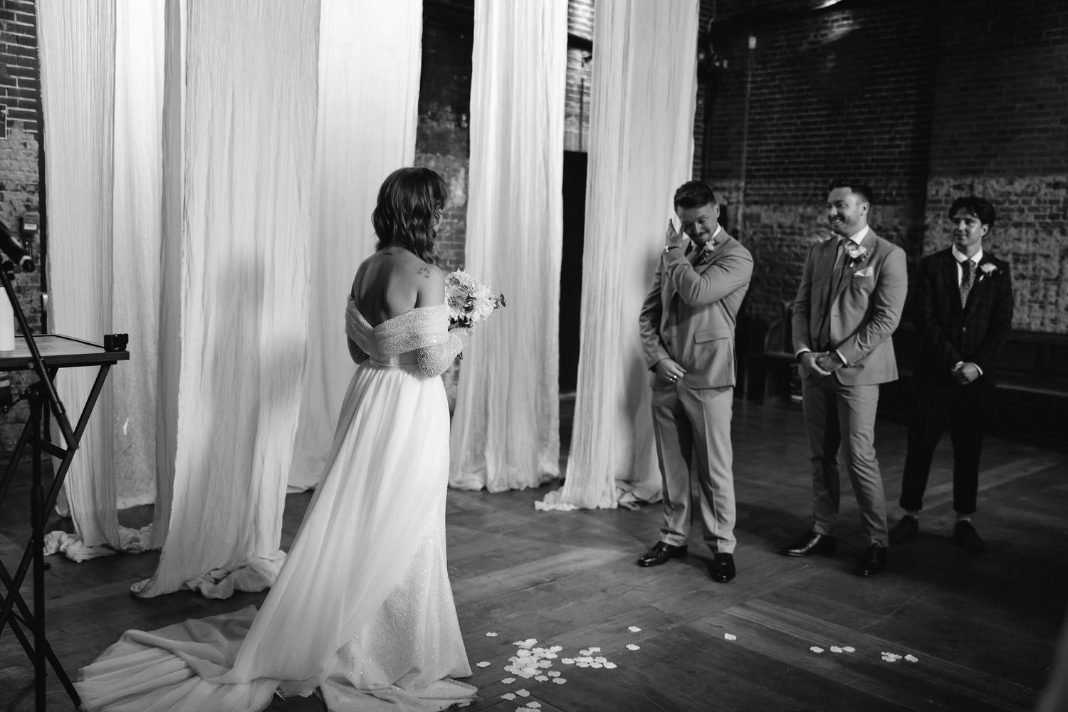 Wedding guests enjoy dancing in a venue decorated with elegant white drapes.